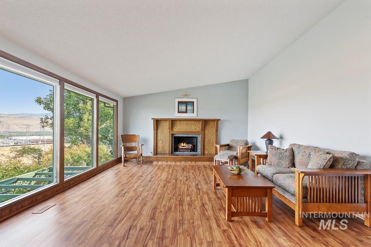 Living room with vaulted ceiling, wood finished floors, a premium fireplace, and a mountain view