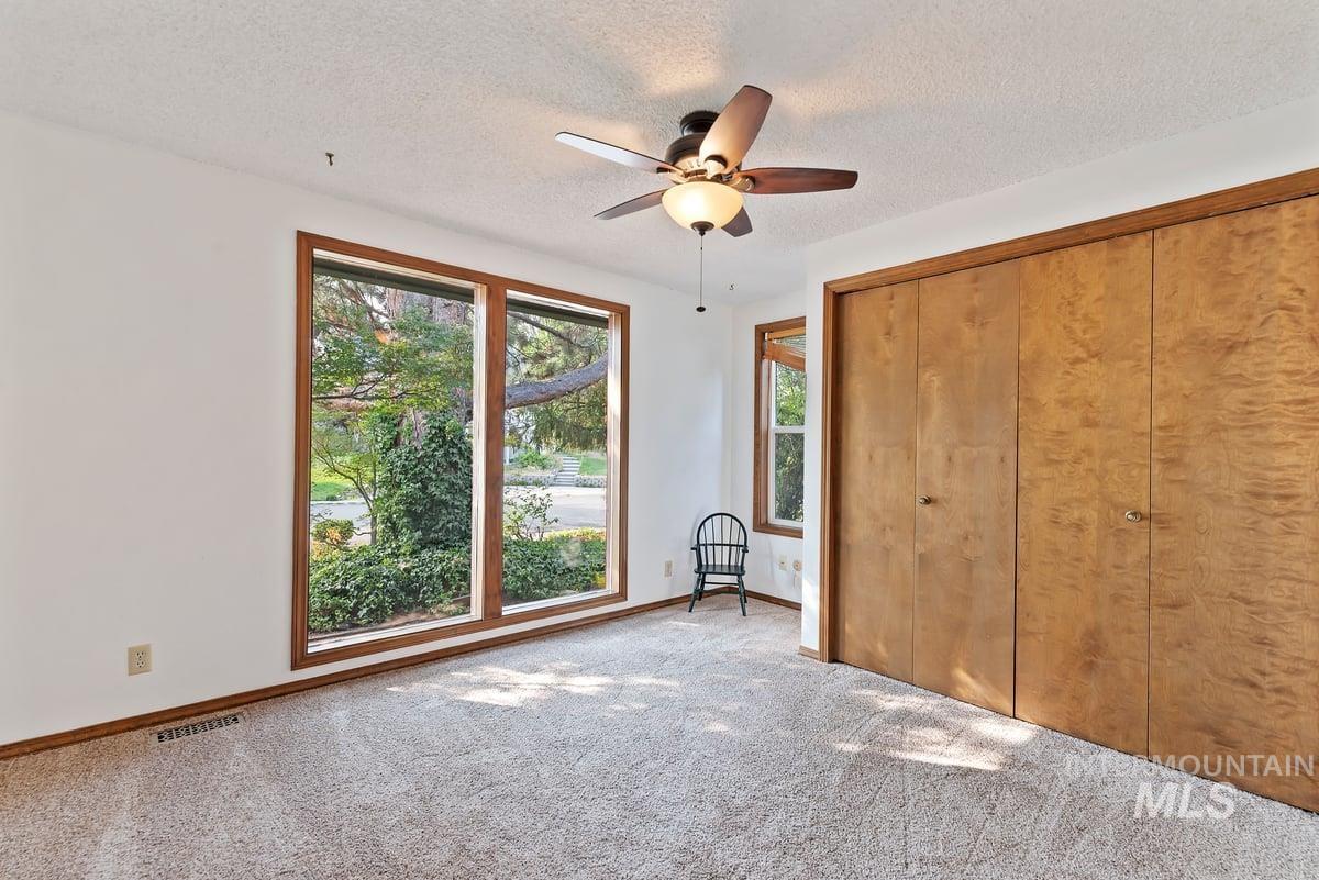 Unfurnished bedroom with carpet, a textured ceiling, ceiling fan, and a closet
