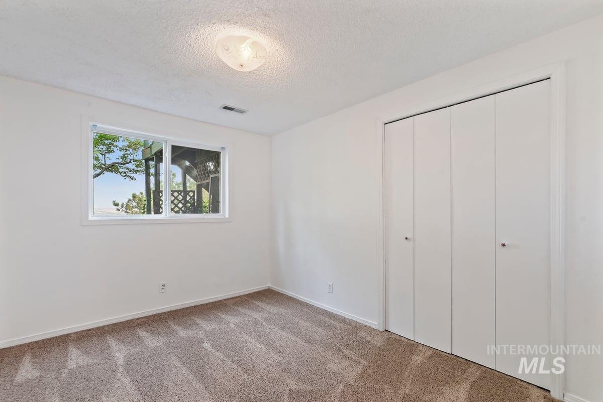 Unfurnished bedroom with a textured ceiling, carpet floors, and a closet