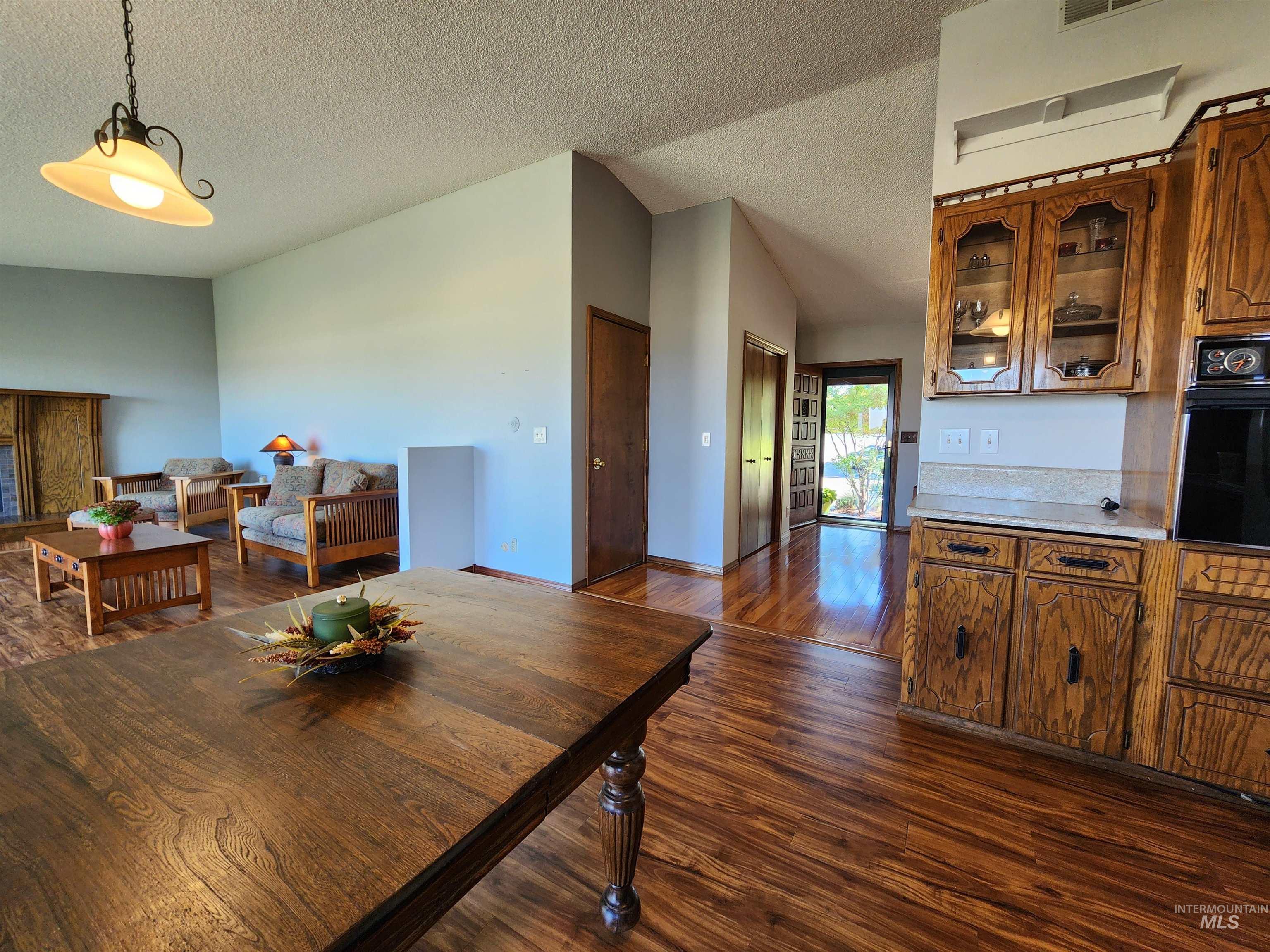 Dining area featuring dark wood-style floors, a textured ceiling, and vaulted ceiling