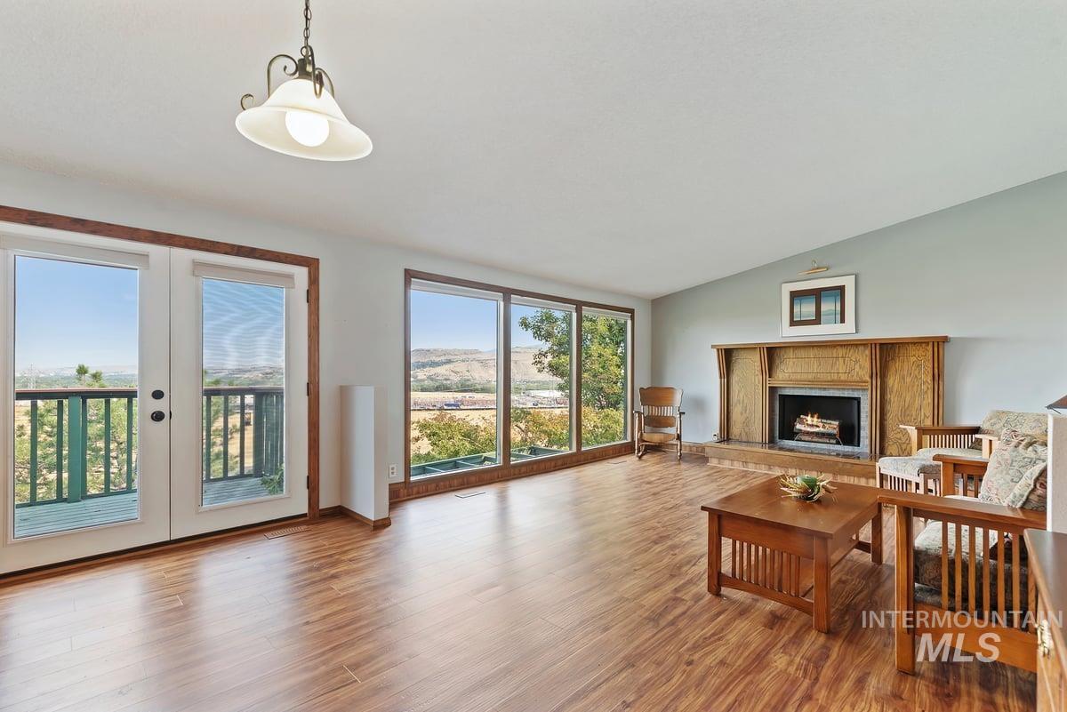 Living area featuring a premium fireplace, light wood finished floors, lofted ceiling, and french doors