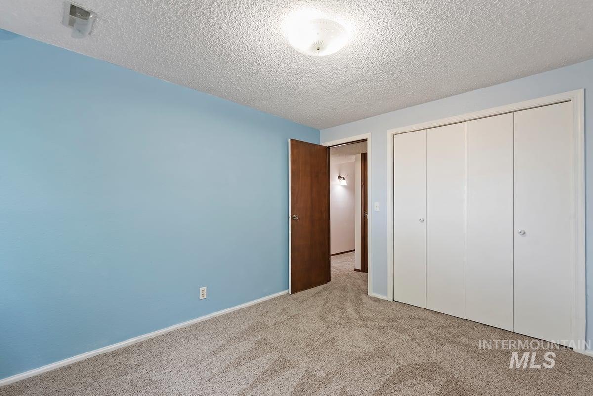 Unfurnished bedroom featuring carpet flooring, a closet, and a textured ceiling