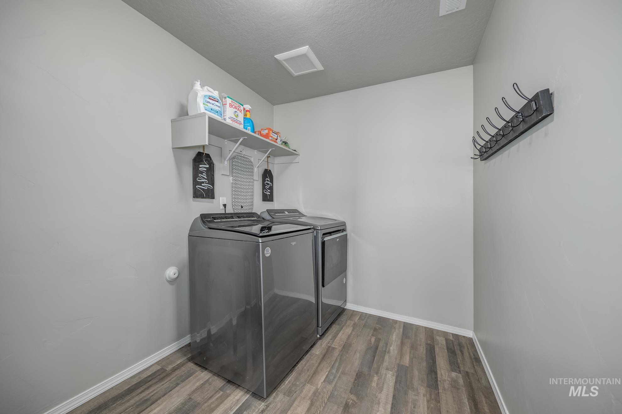 Dedicated laundry area featuring wood-finish flooring and light gray walls