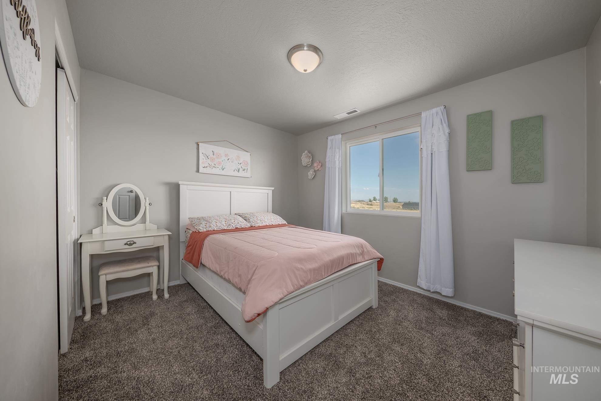 Spacious room featuring neutral carpeting, light gray wall paint, and a large window with white trim