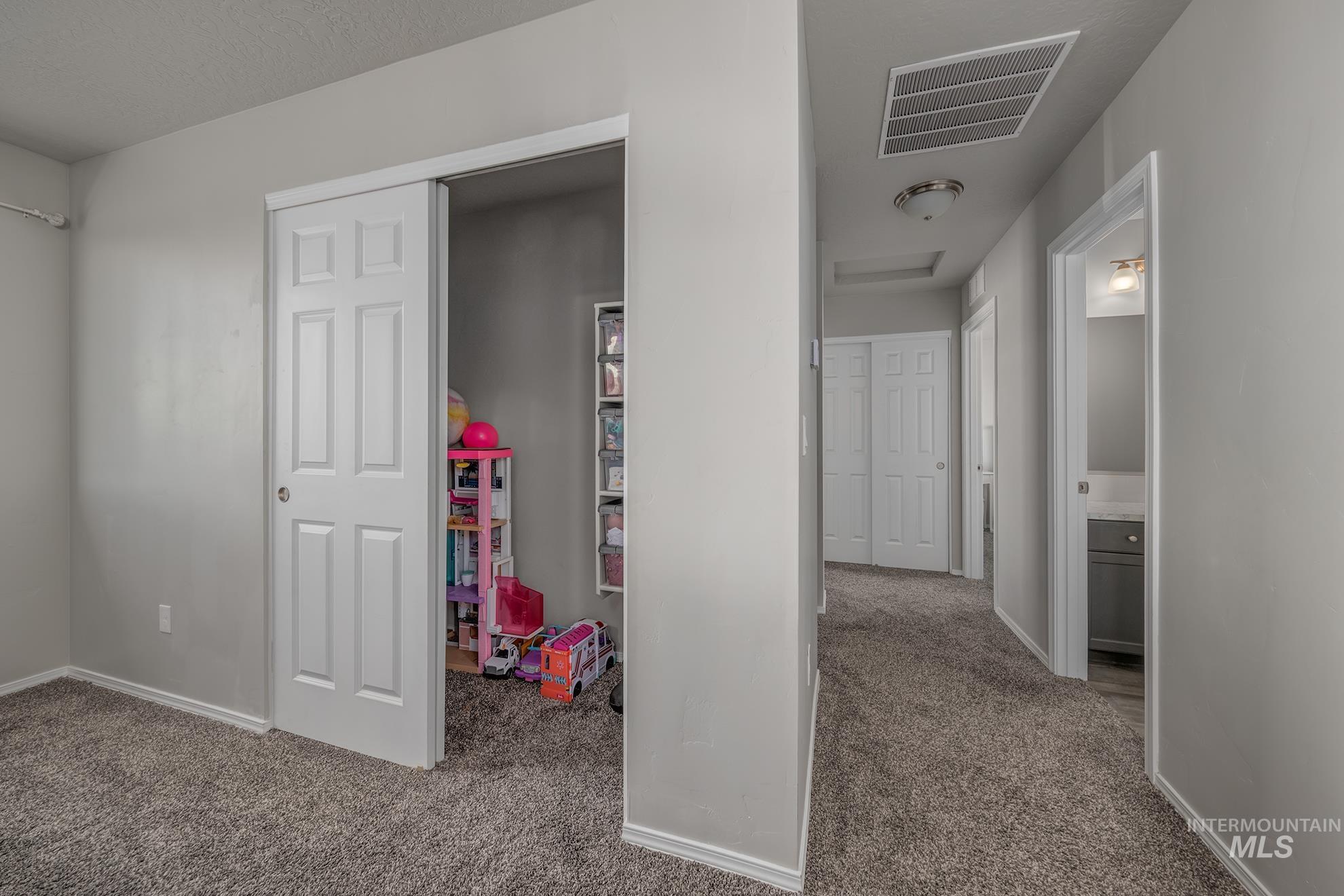 Hallway featuring gray carpet flooring, white trim, and light gray wall paint
