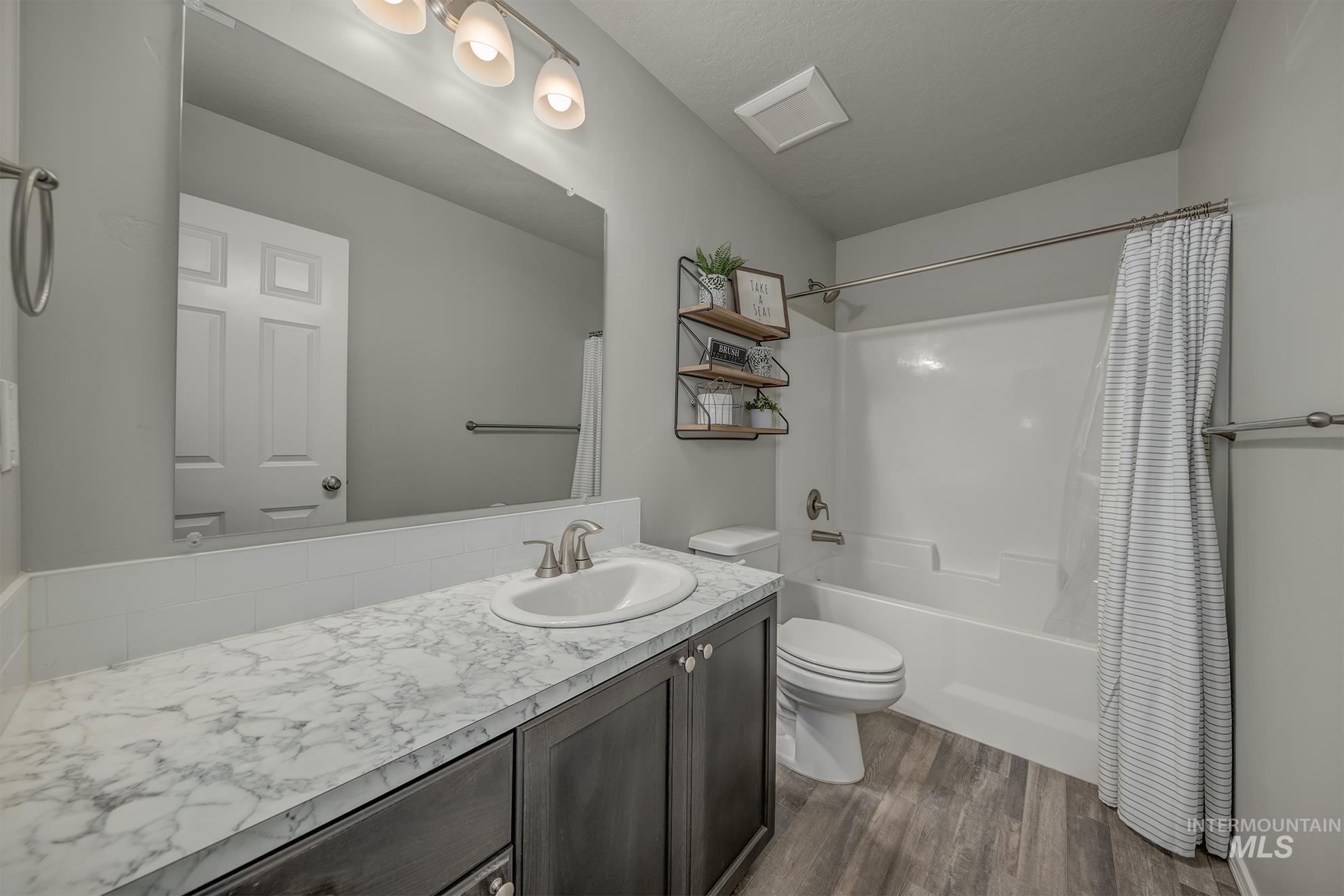 Bathroom featuring a single vanity with a white-finish countertop, undermount sink, and brushed nickel faucet