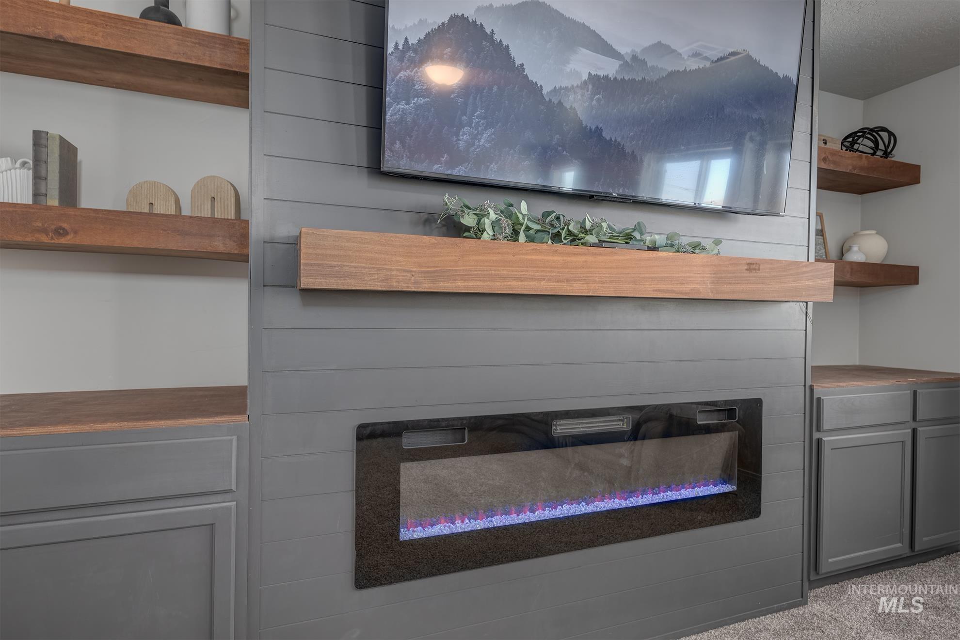 Built-in entertainment wall featuring a mounted electric fireplace, wood-finish mantel, and shiplap paneling