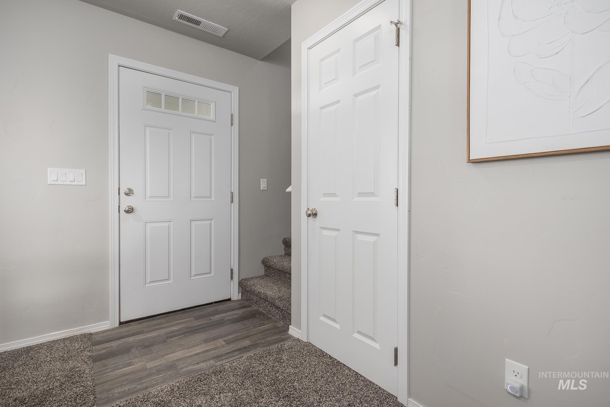 Entryway featuring a white paneled door with glass inserts, wood-finish flooring, and a carpeted staircase