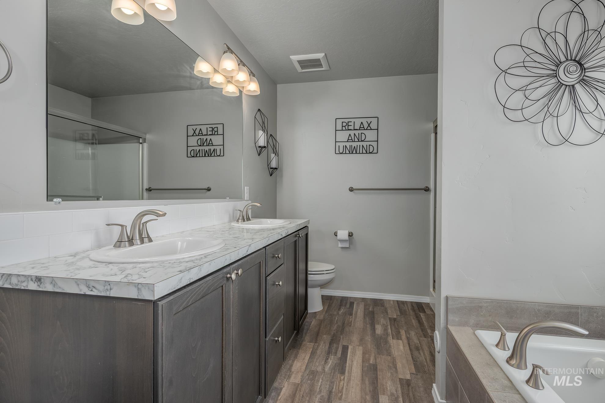 Dual vanity with wood-finish cabinetry, white countertop, and integrated sinks