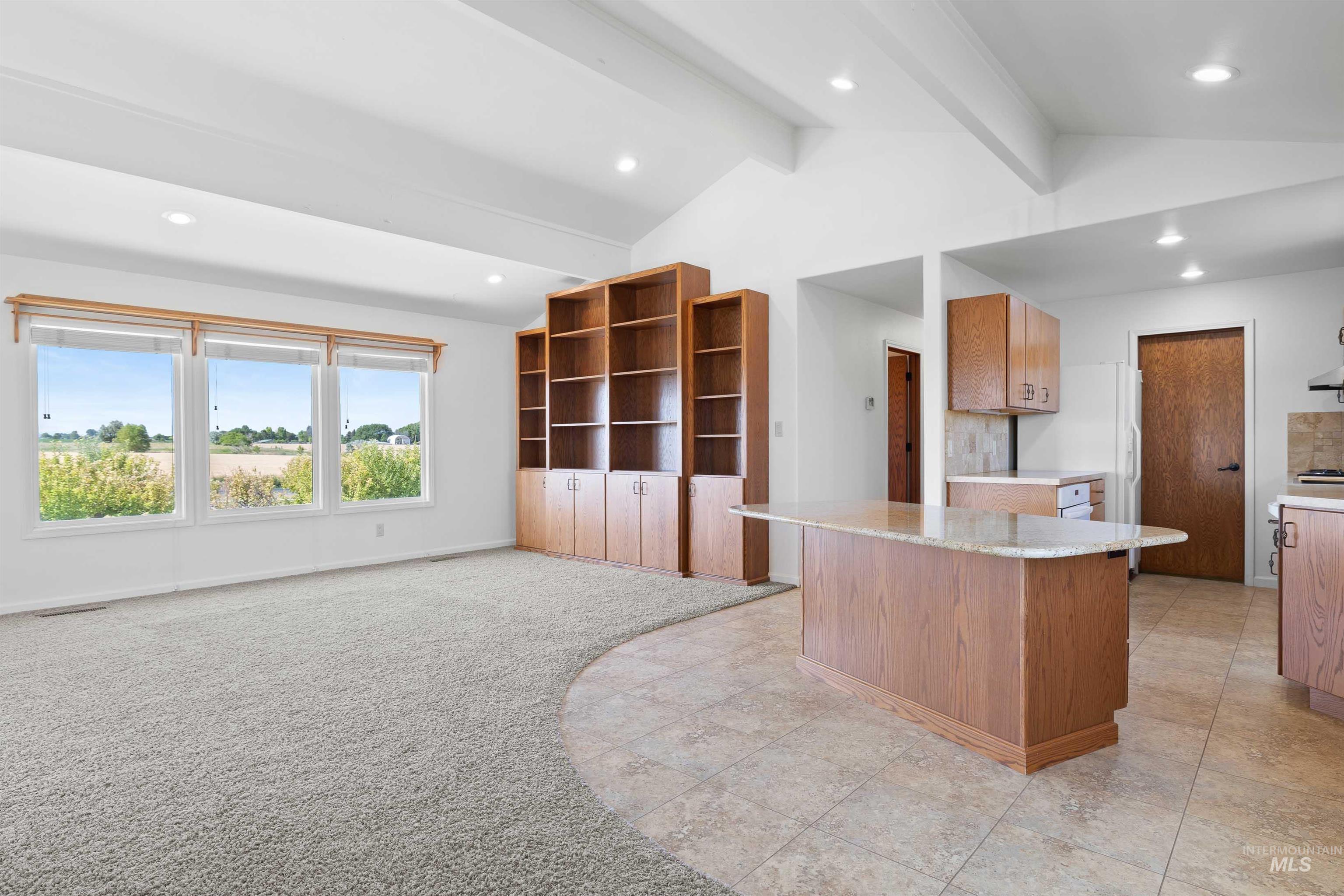 Kitchen featuring light countertops, recessed lighting, a center island, brown cabinetry, and white refrigerator with ice dispenser