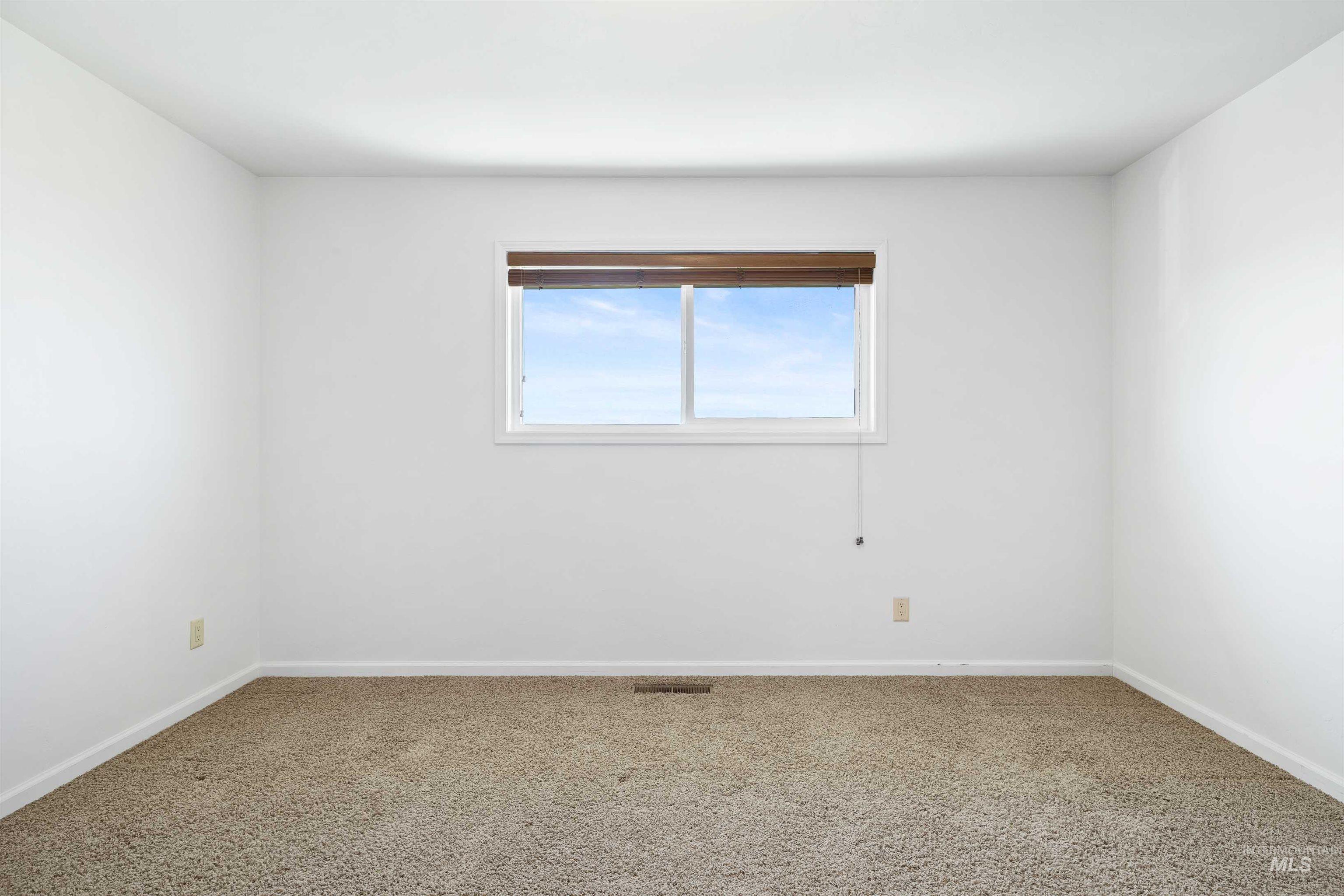 Carpeted empty room featuring baseboards