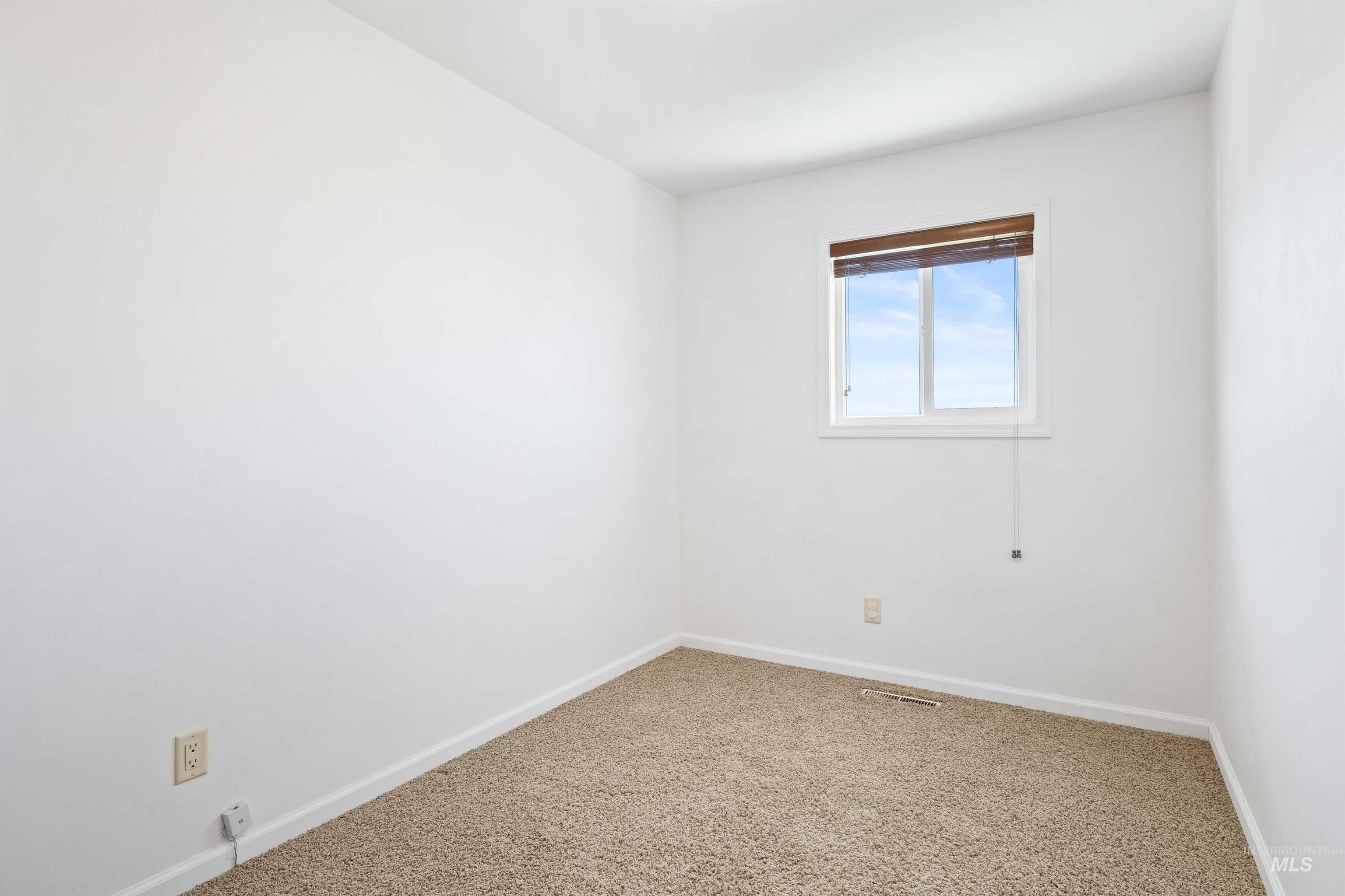 Carpeted spare room featuring baseboards