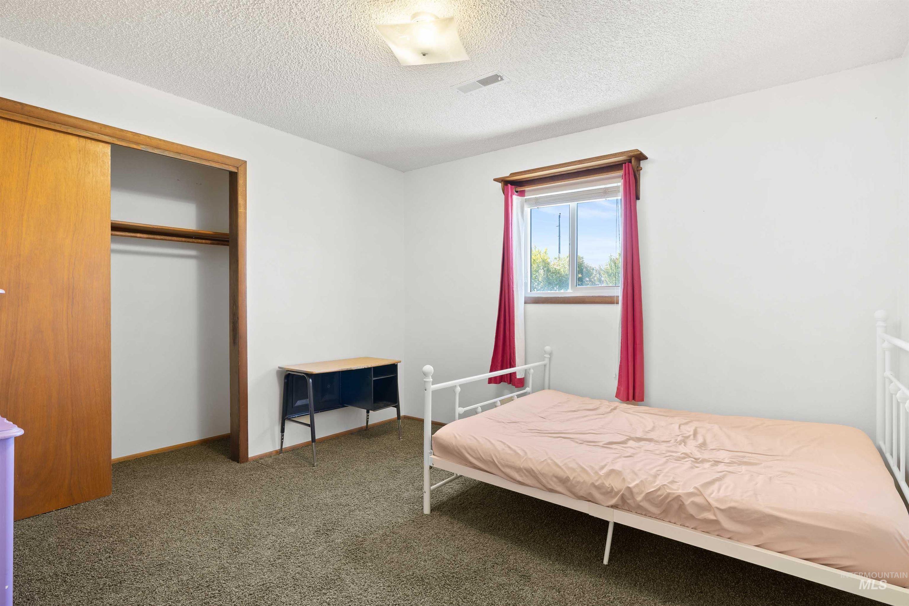 Carpeted bedroom featuring a closet and a textured ceiling