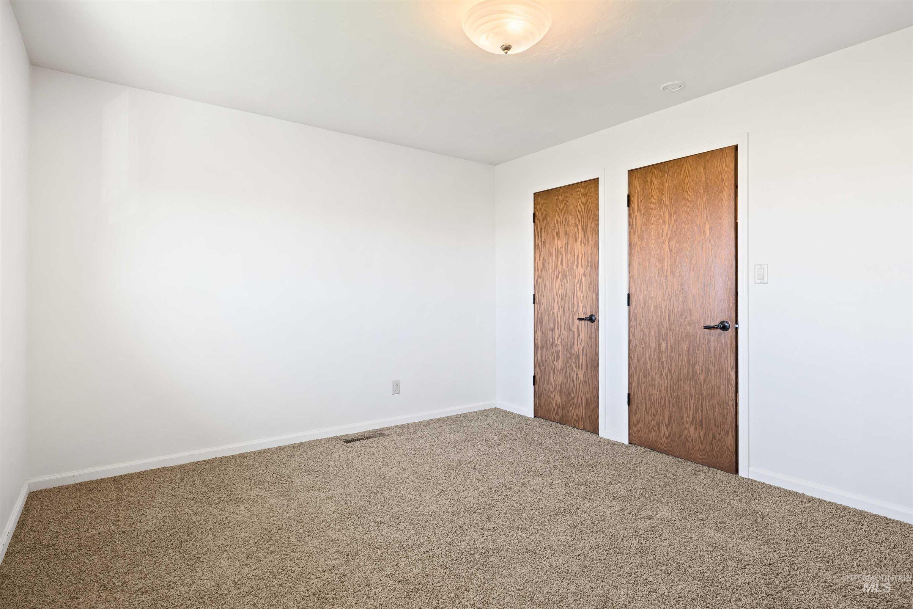 Unfurnished bedroom featuring two closets and carpet flooring