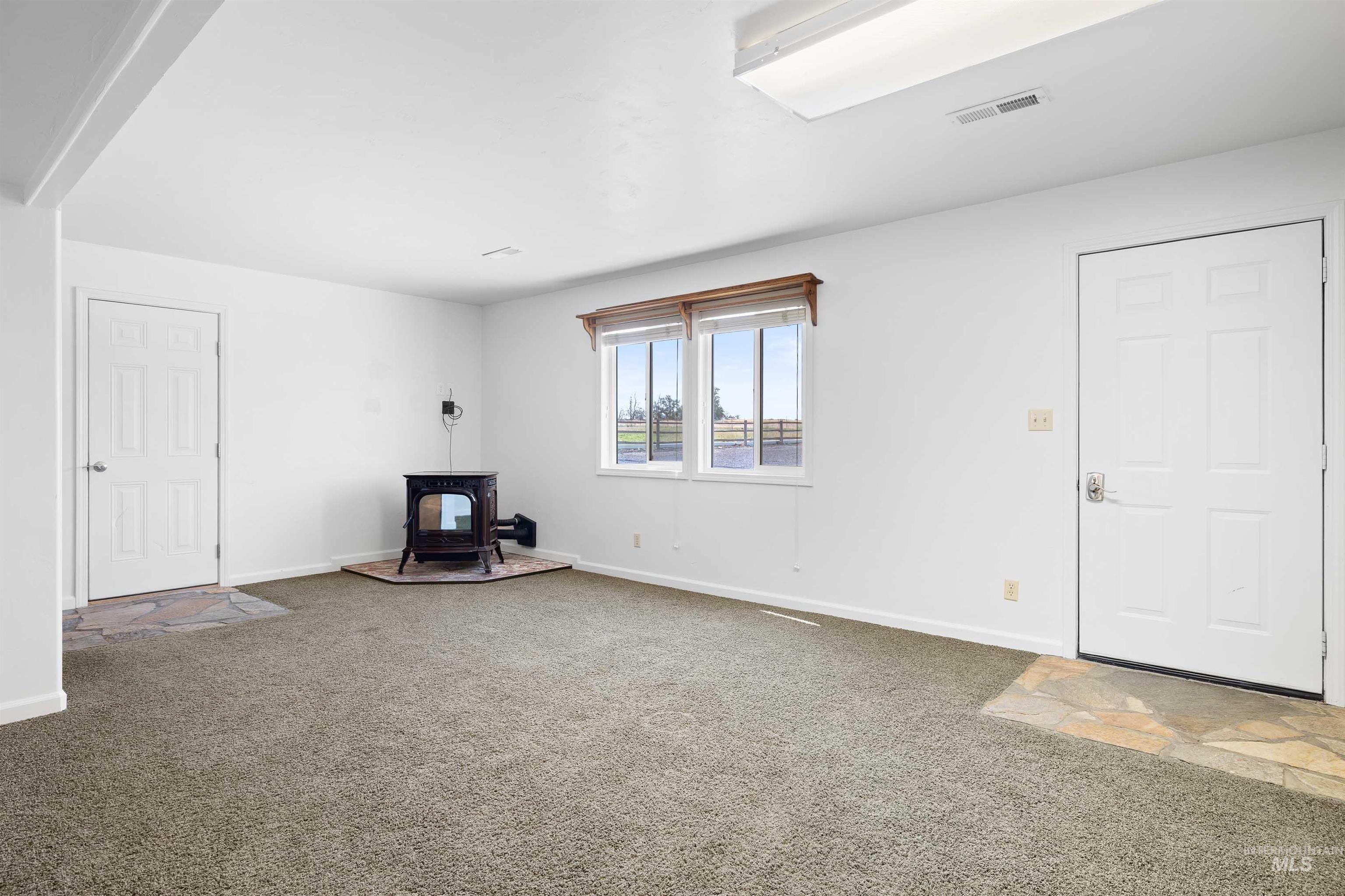 Unfurnished living room featuring a wood stove and carpet floors