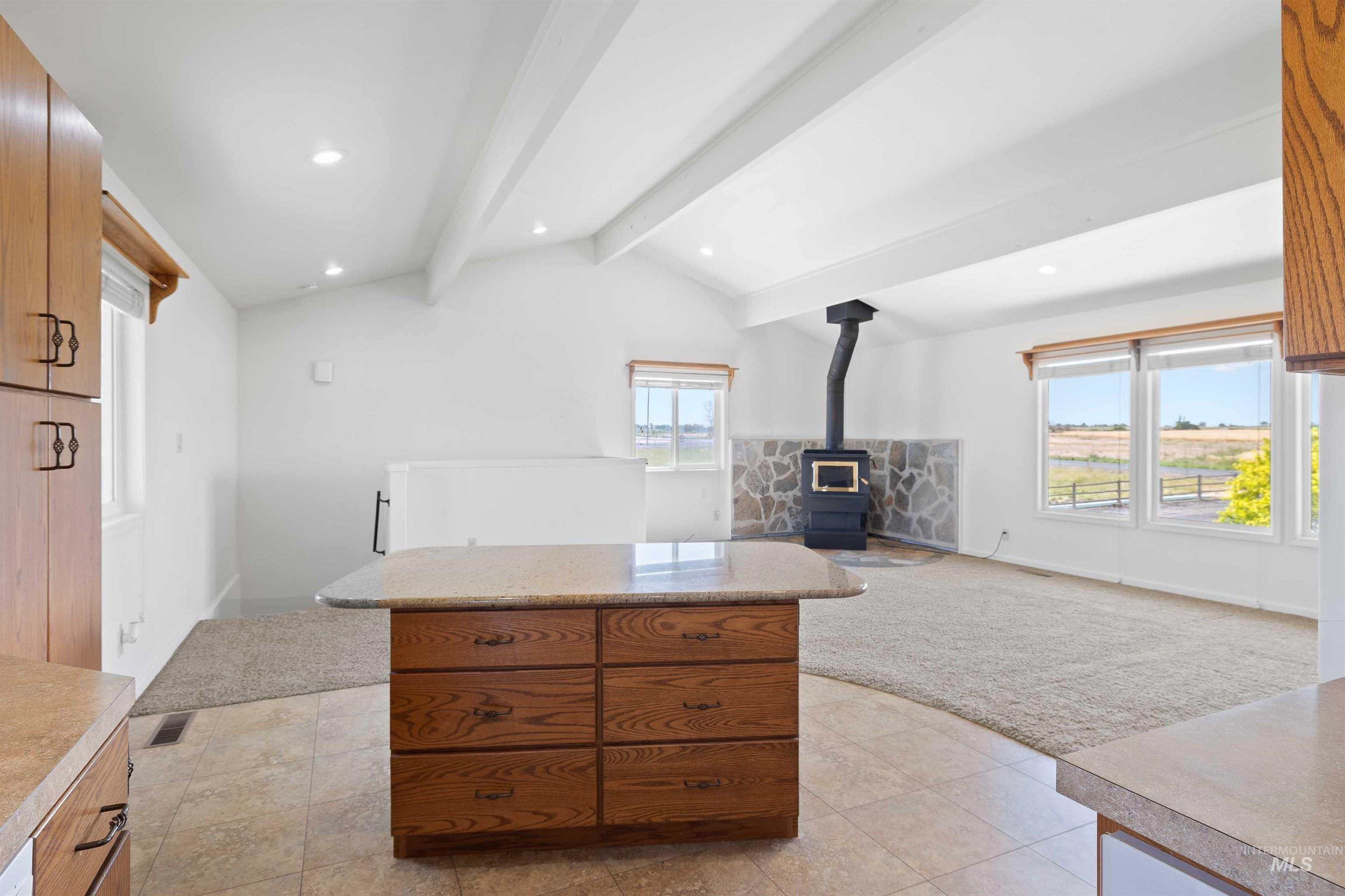 Kitchen featuring a wood stove, light countertops, recessed lighting, brown cabinetry, and open floor plan