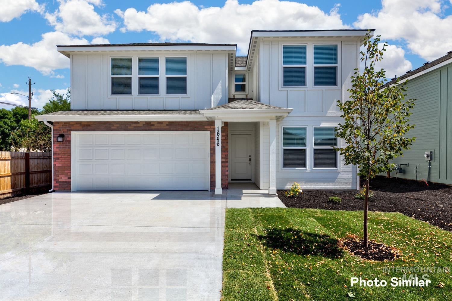 View of front facade with board and batten siding, driveway, brick siding, and an attached garage