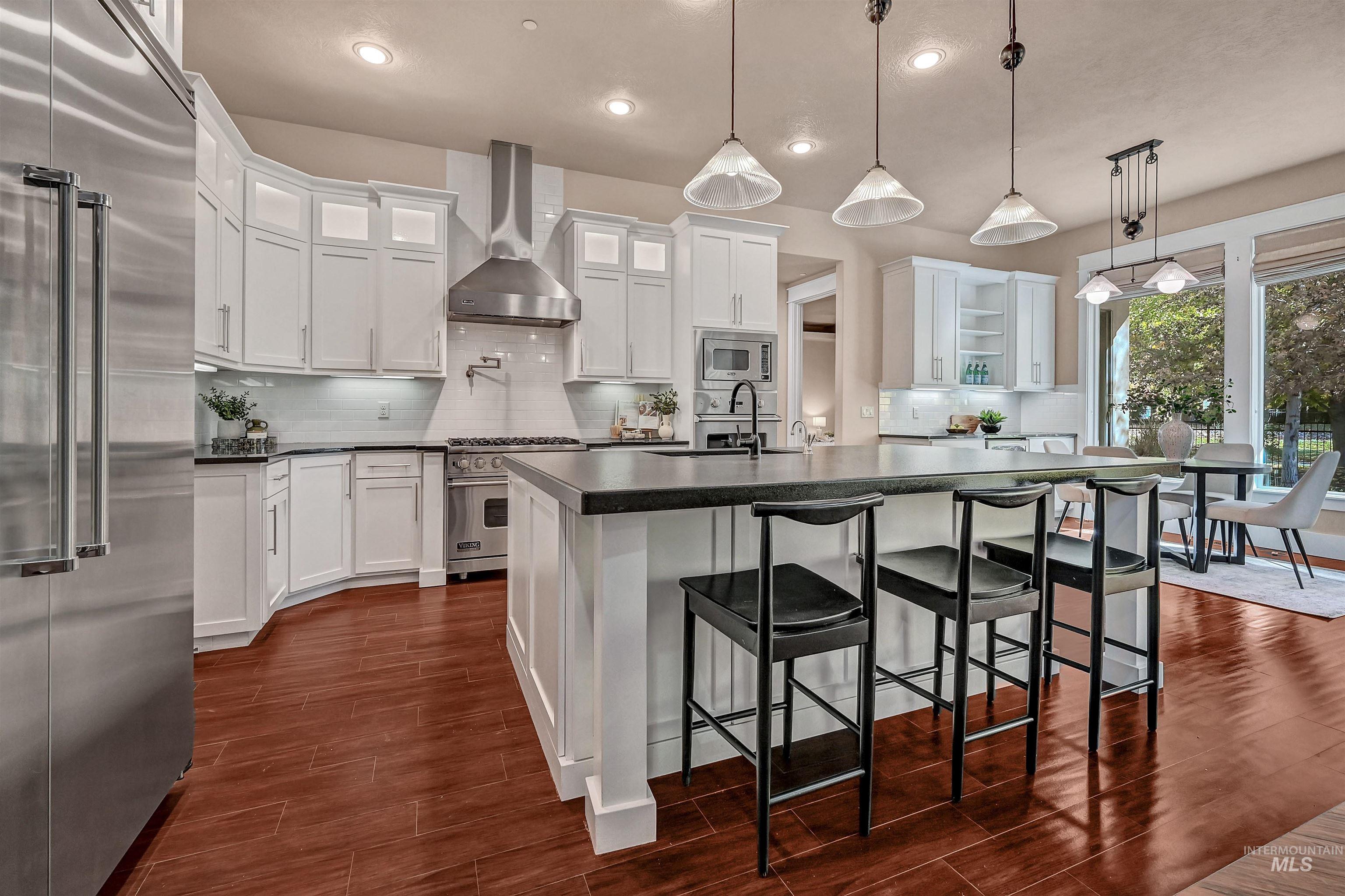 Kitchen featuring dark countertops, decorative backsplash, premium appliances, a breakfast bar, and recessed lighting