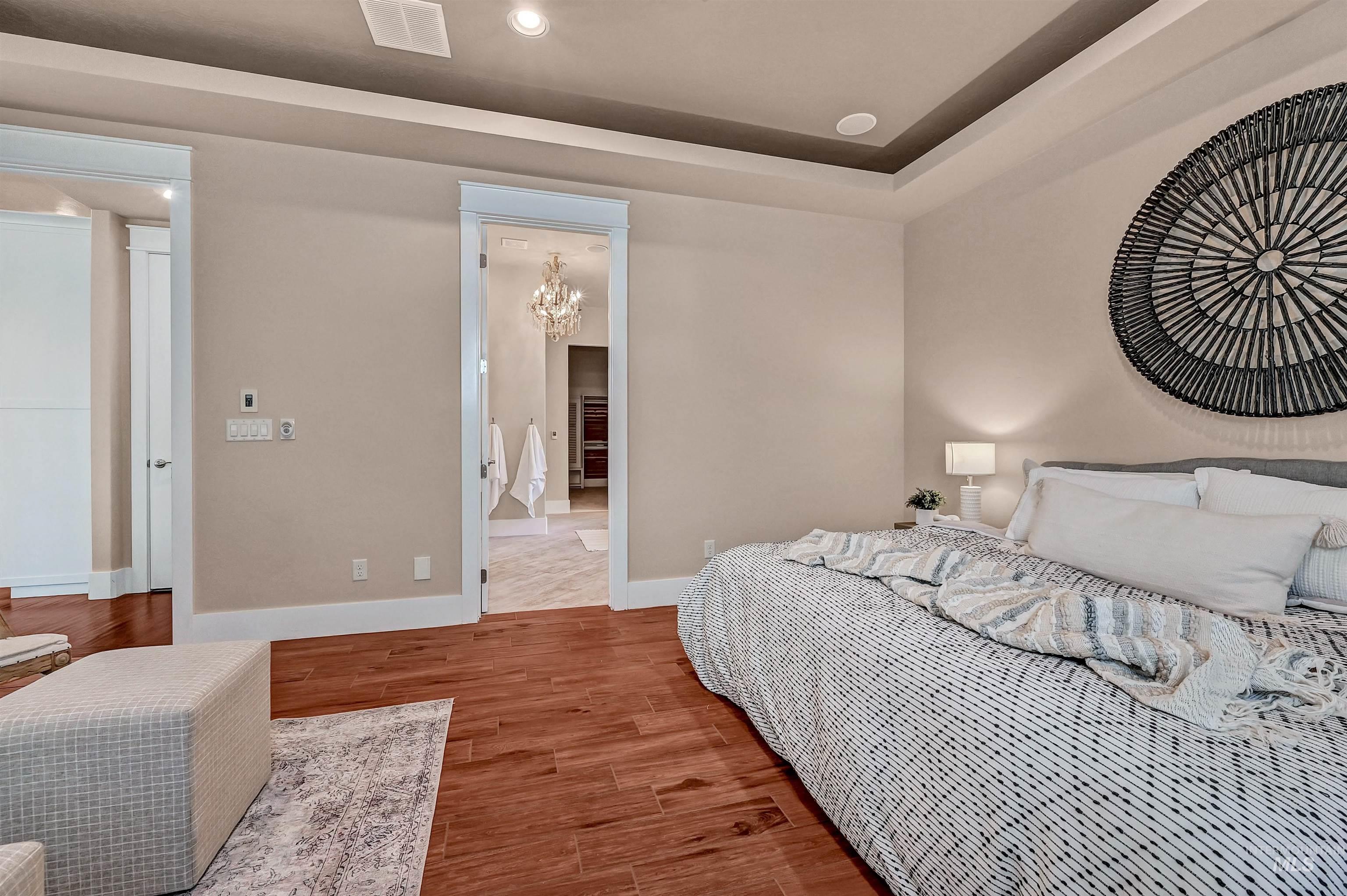 Bedroom featuring a chandelier, wood finished floors, a tray ceiling, and recessed lighting