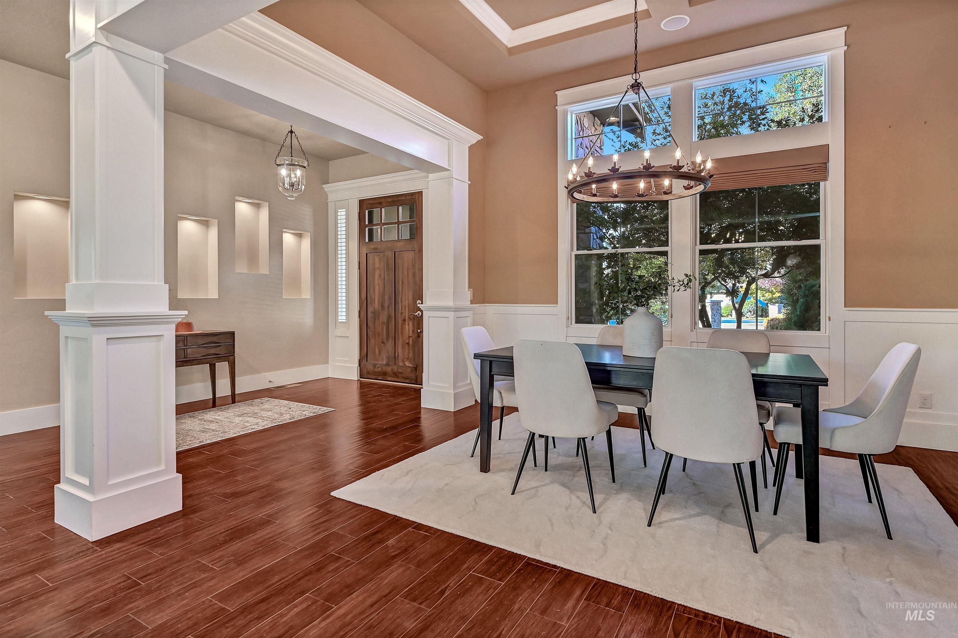 Dining room featuring dark wood-style floors, a chandelier, and a towering ceiling