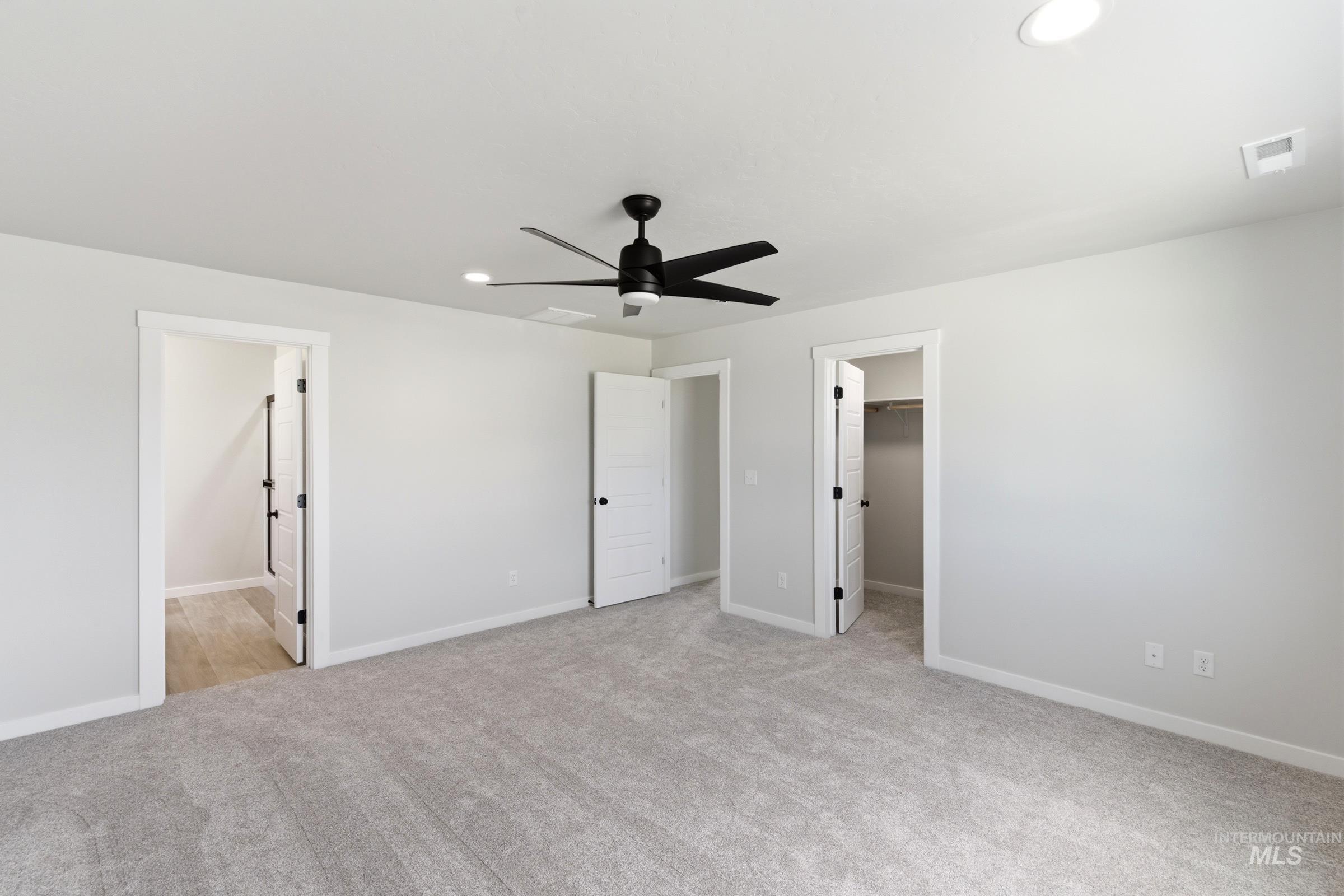 Spacious room featuring light gray carpeting, recessed lighting, and a modern black ceiling fan
