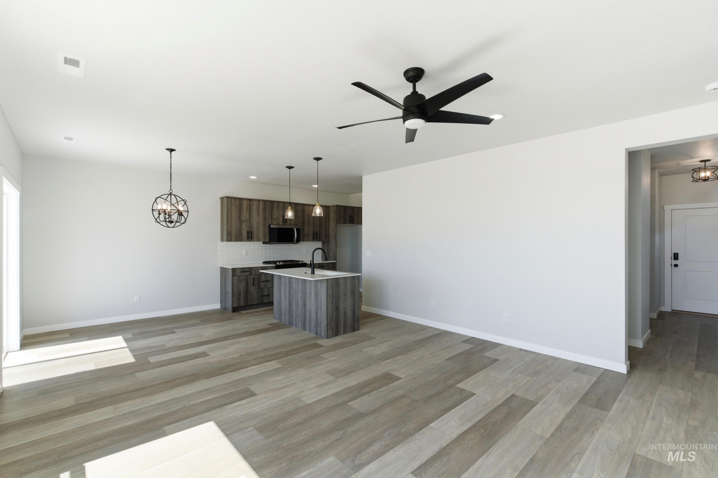 Open-concept living area featuring wood-finish flooring, a contemporary ceiling fan, and recessed lighting
