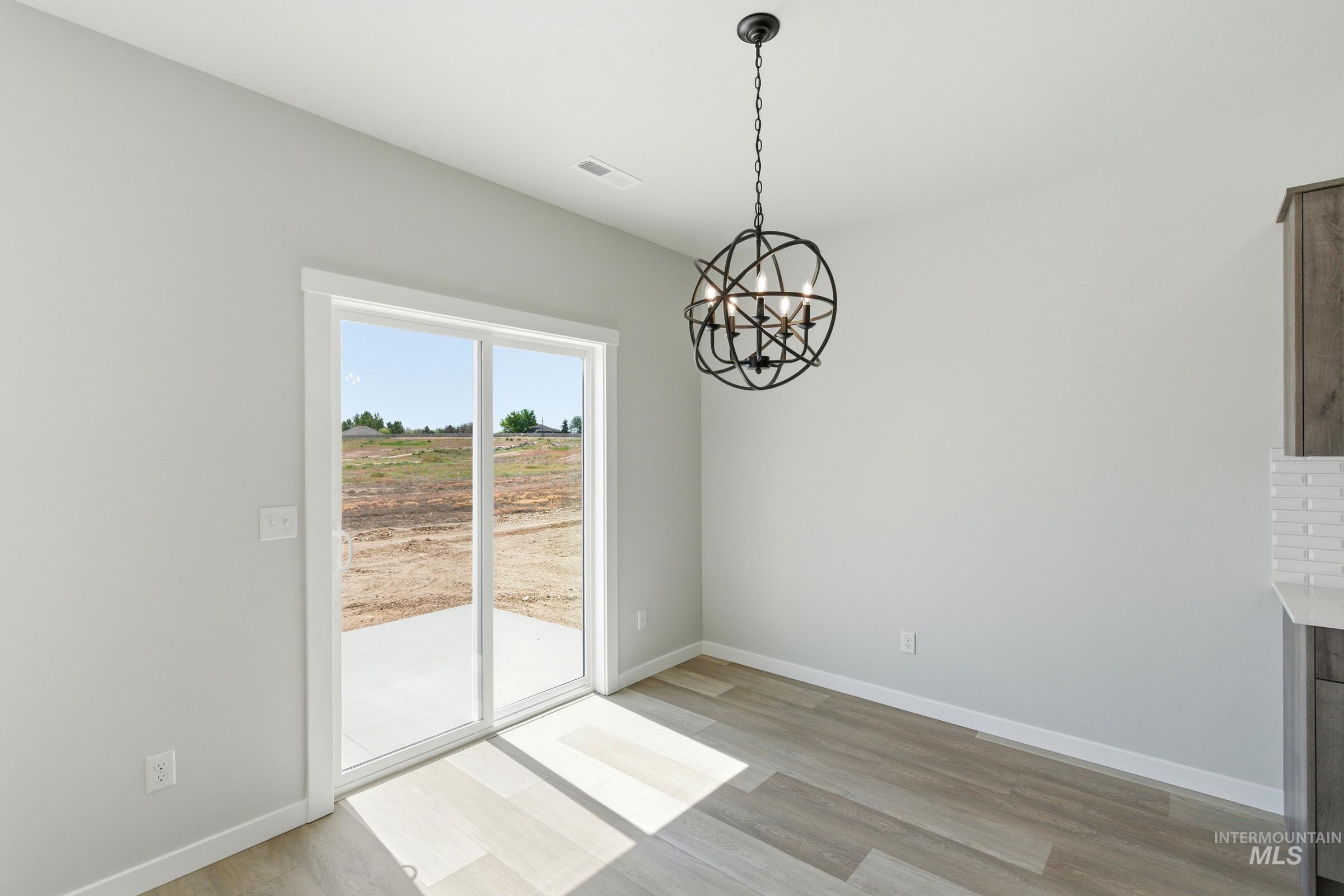 Dining area featuring a modern black orb chandelier, wood-finish flooring, and a sliding glass door to an outdoor patio