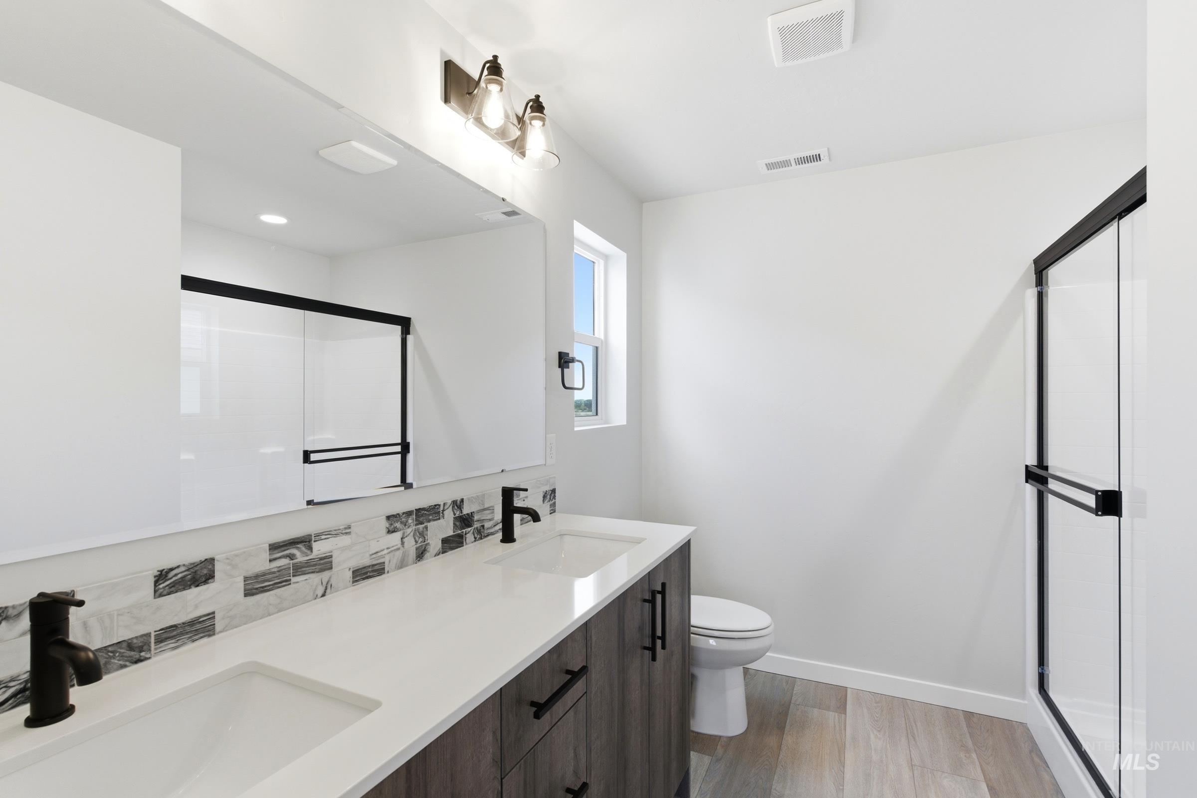 Bathroom featuring a dual vanity with white countertops, dark wood-finish cabinetry, and matte black fixtures