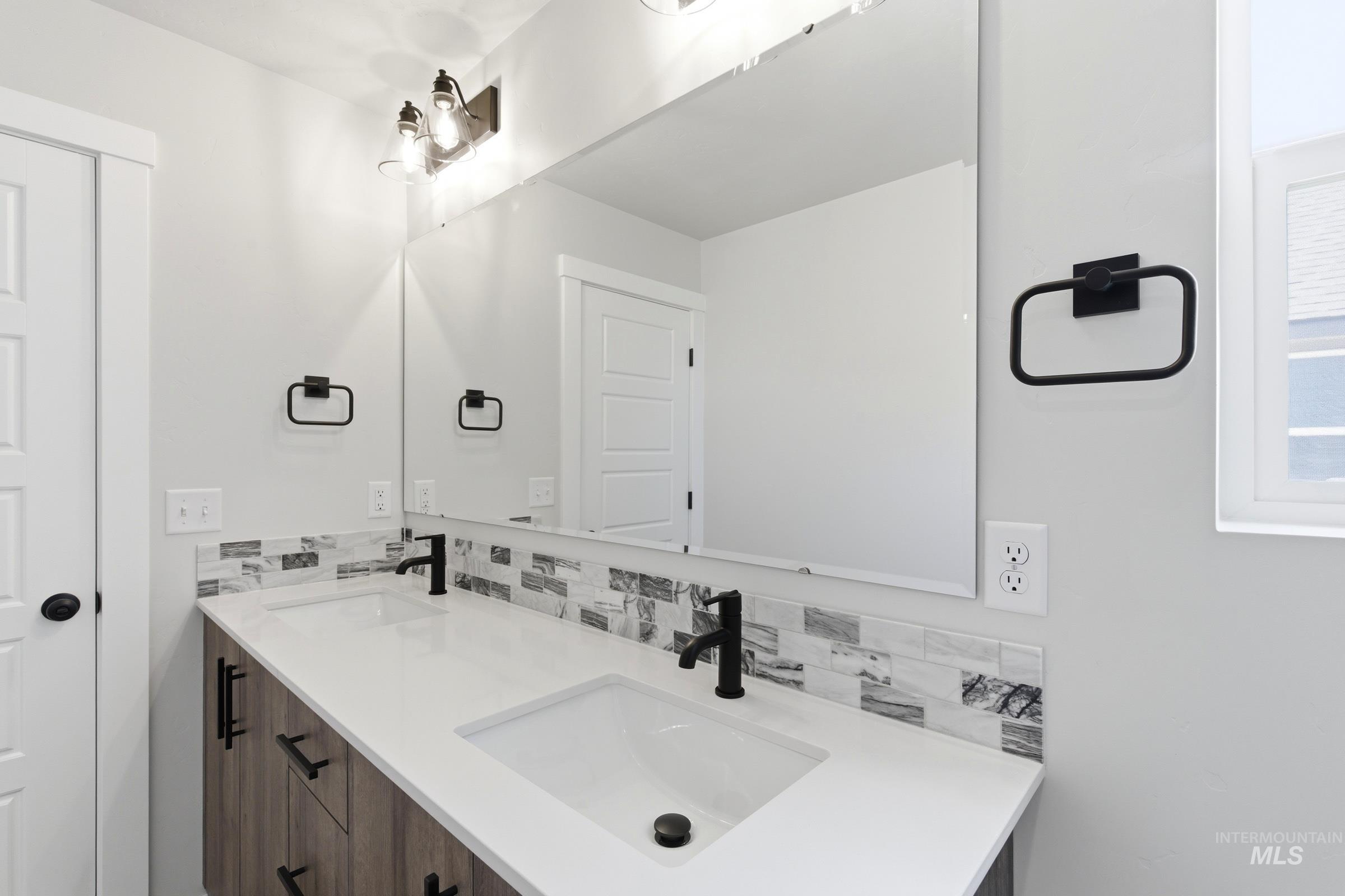 Bathroom vanity featuring dual under-mount sinks, white countertops, and a wood-finish cabinet