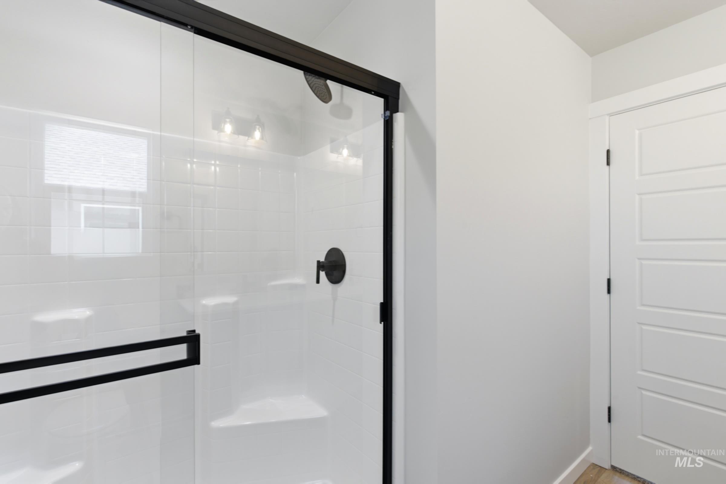 Glass-enclosed shower featuring a matte black frame and hardware, white subway tile surround, and an integrated bench seat