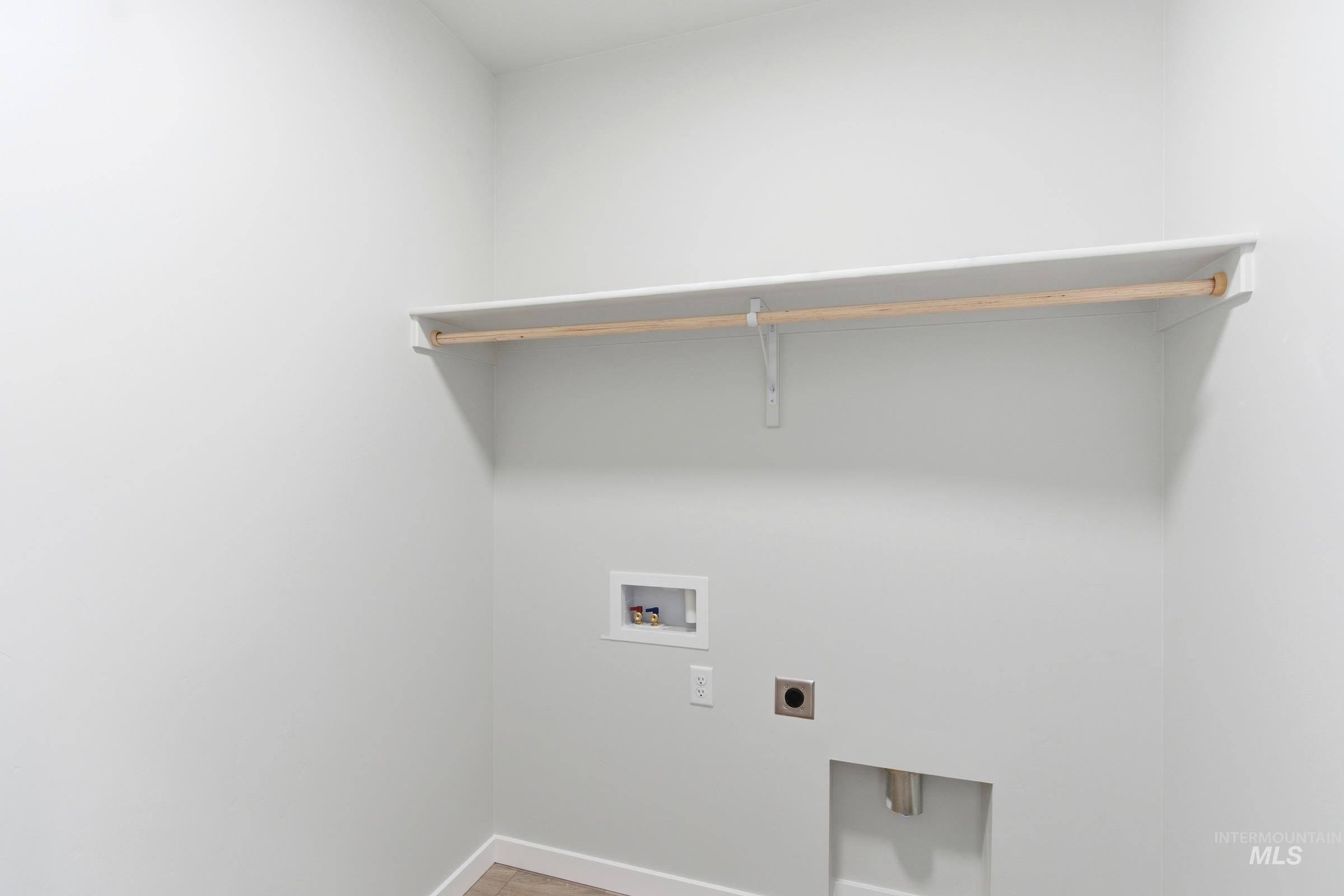 Dedicated utility space featuring a wood-finish hanging rod and overhead shelving