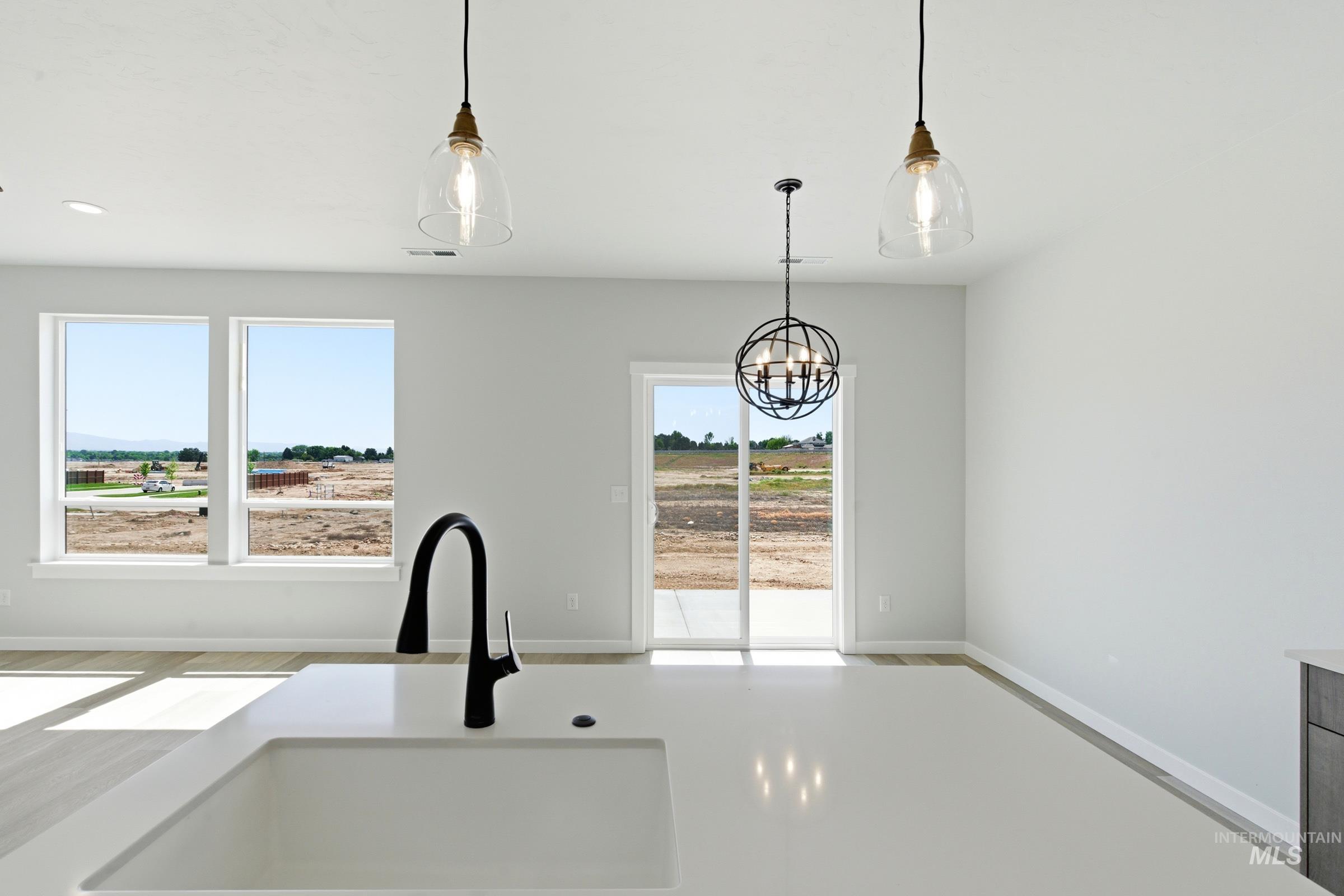 Kitchen island featuring an integrated sink with a matte black high-arc faucet, two pendant lights with clear glass shades, and light wood-finish flooring