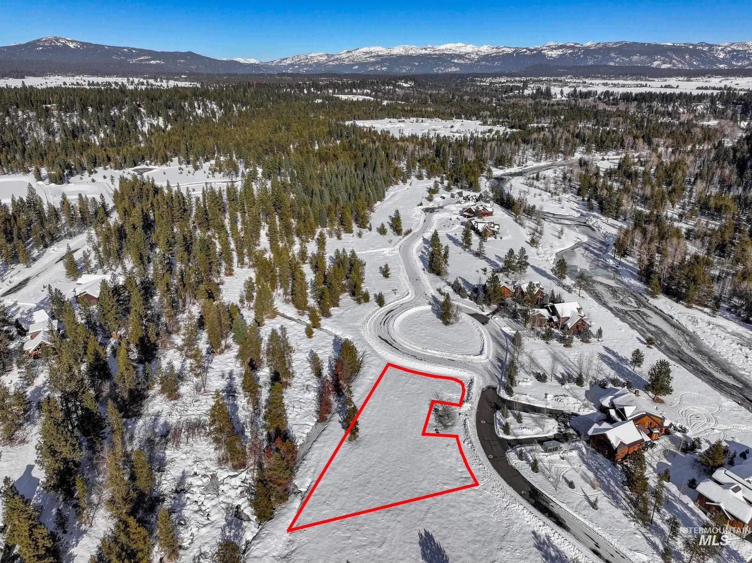 Snowy aerial view with a mountain view and property parcel outlined