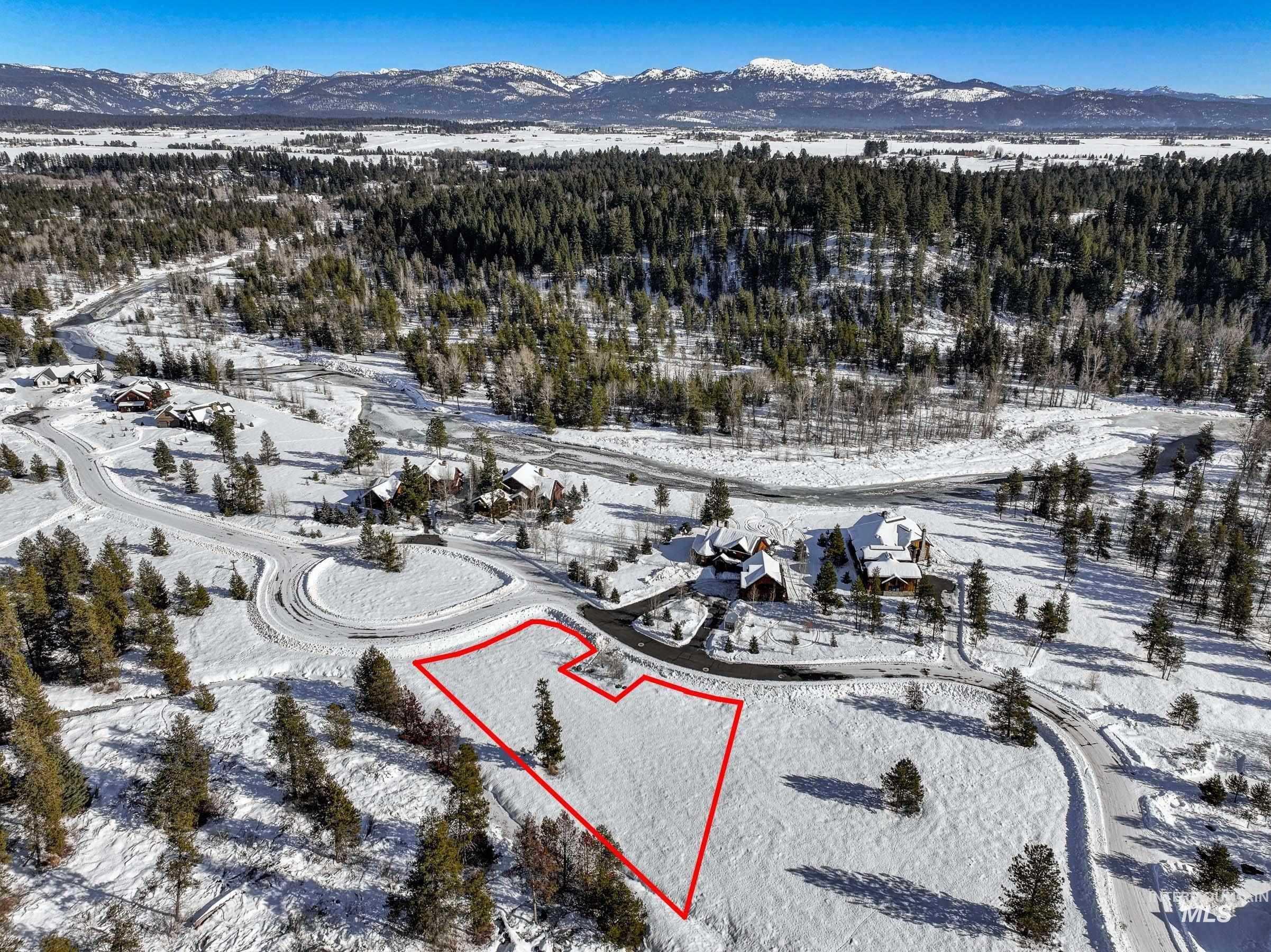 Snowy aerial view with a mountain view and property parcel outlined