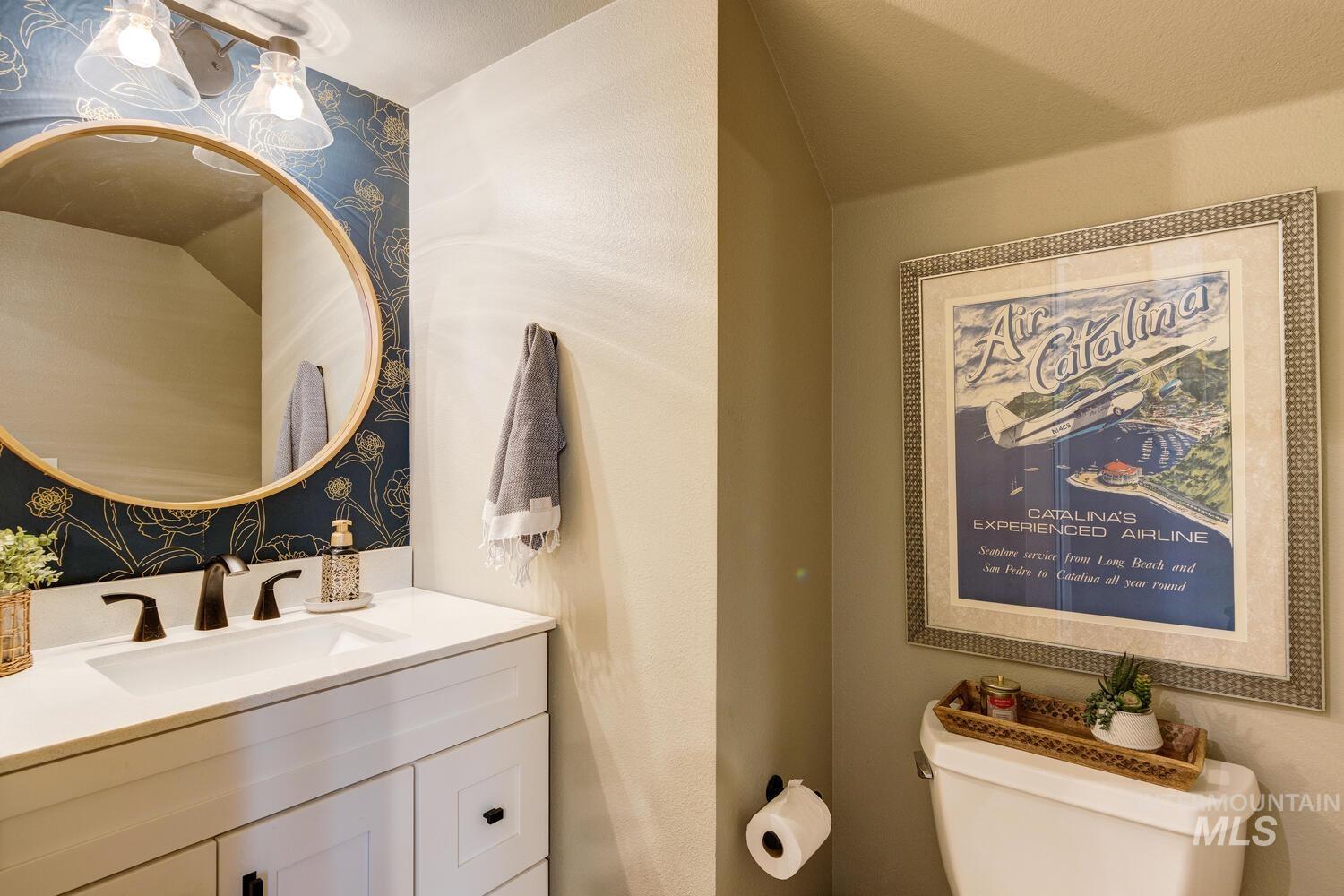 Half bath with vanity and wallpapered walls