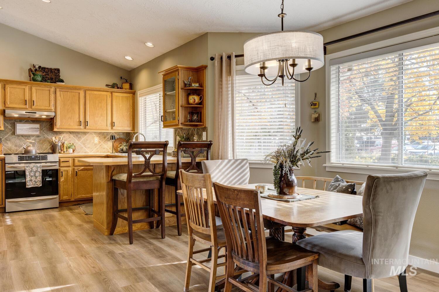 Dining space featuring light wood-style floors, vaulted ceiling, recessed lighting, and a chandelier