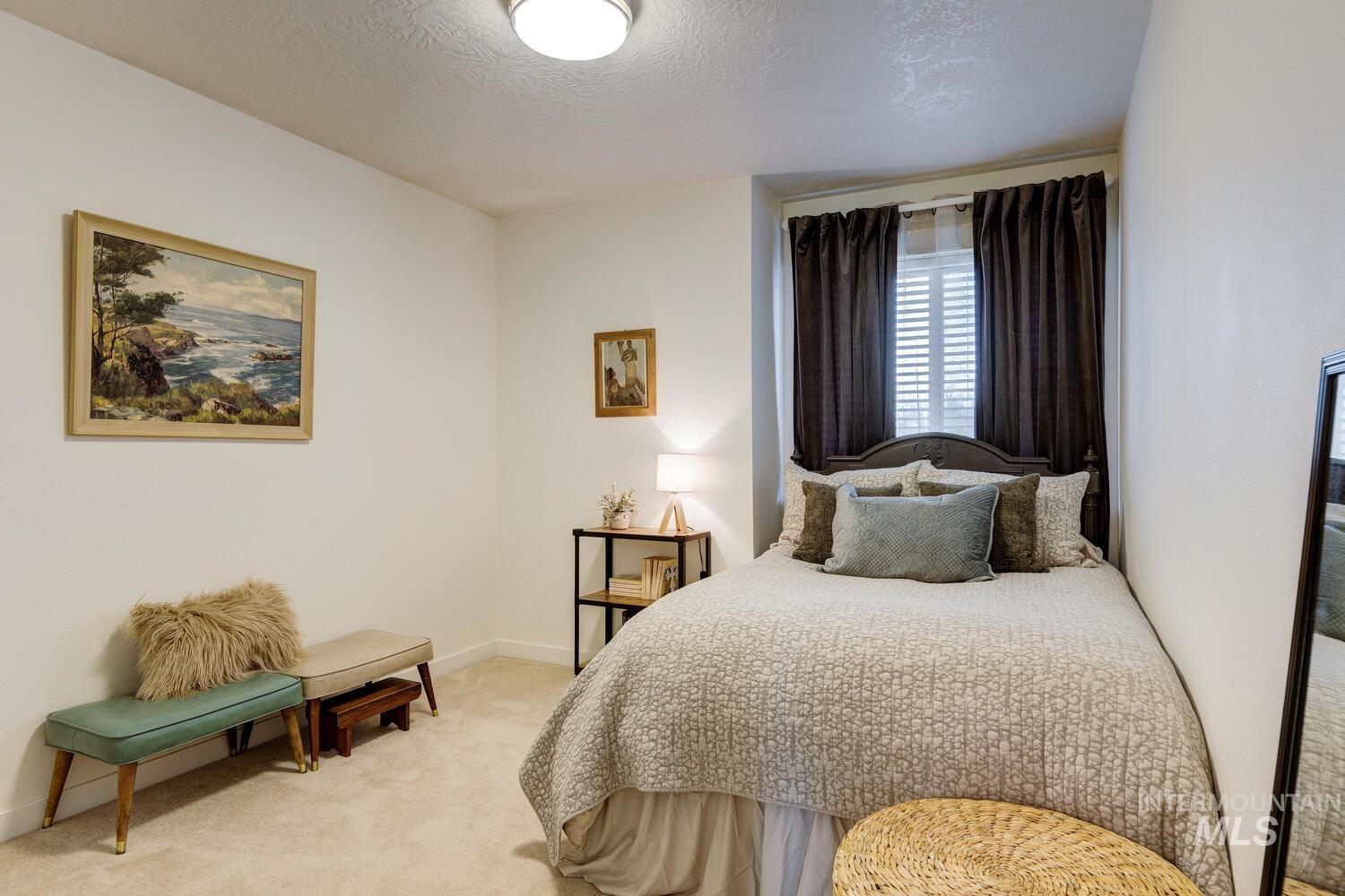 Bedroom with light colored carpet and a textured ceiling