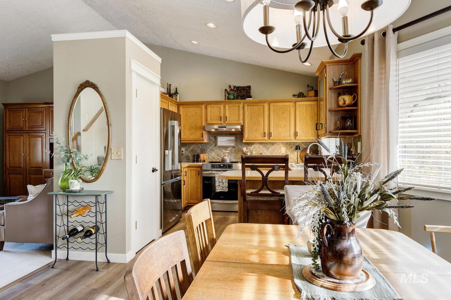 Dining area with vaulted ceiling, light wood-style flooring, a chandelier, and recessed lighting