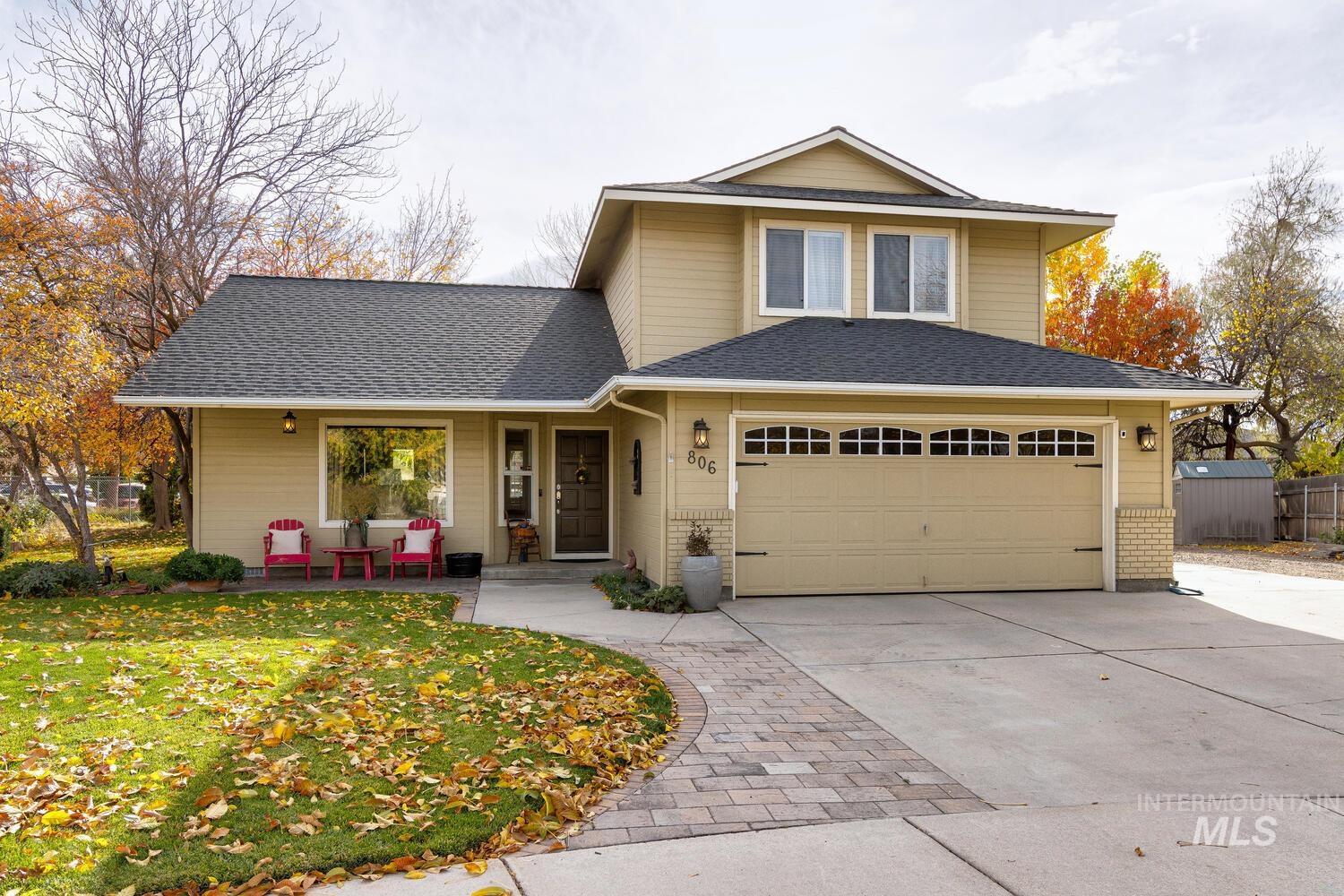 View of front of house featuring driveway, brick siding, and a shingled roof