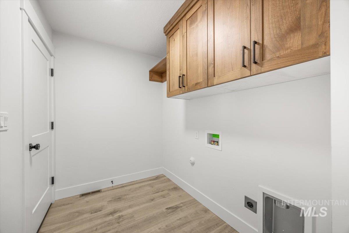Laundry room with light wood-style flooring, cabinet space, hookup for a washing machine, gas dryer hookup, and hookup for an electric dryer