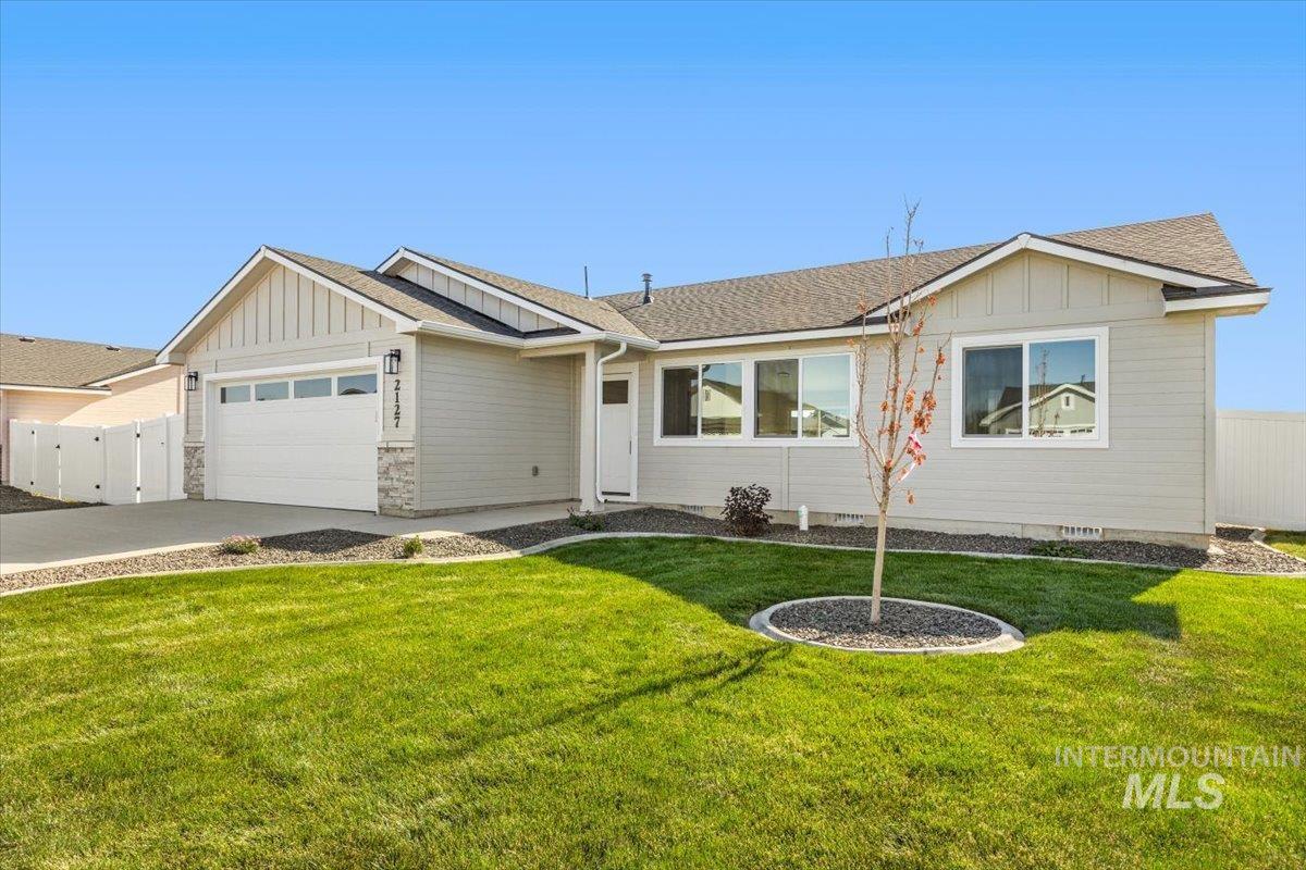 View of front facade featuring board and batten siding, roof with shingles, a garage, and driveway