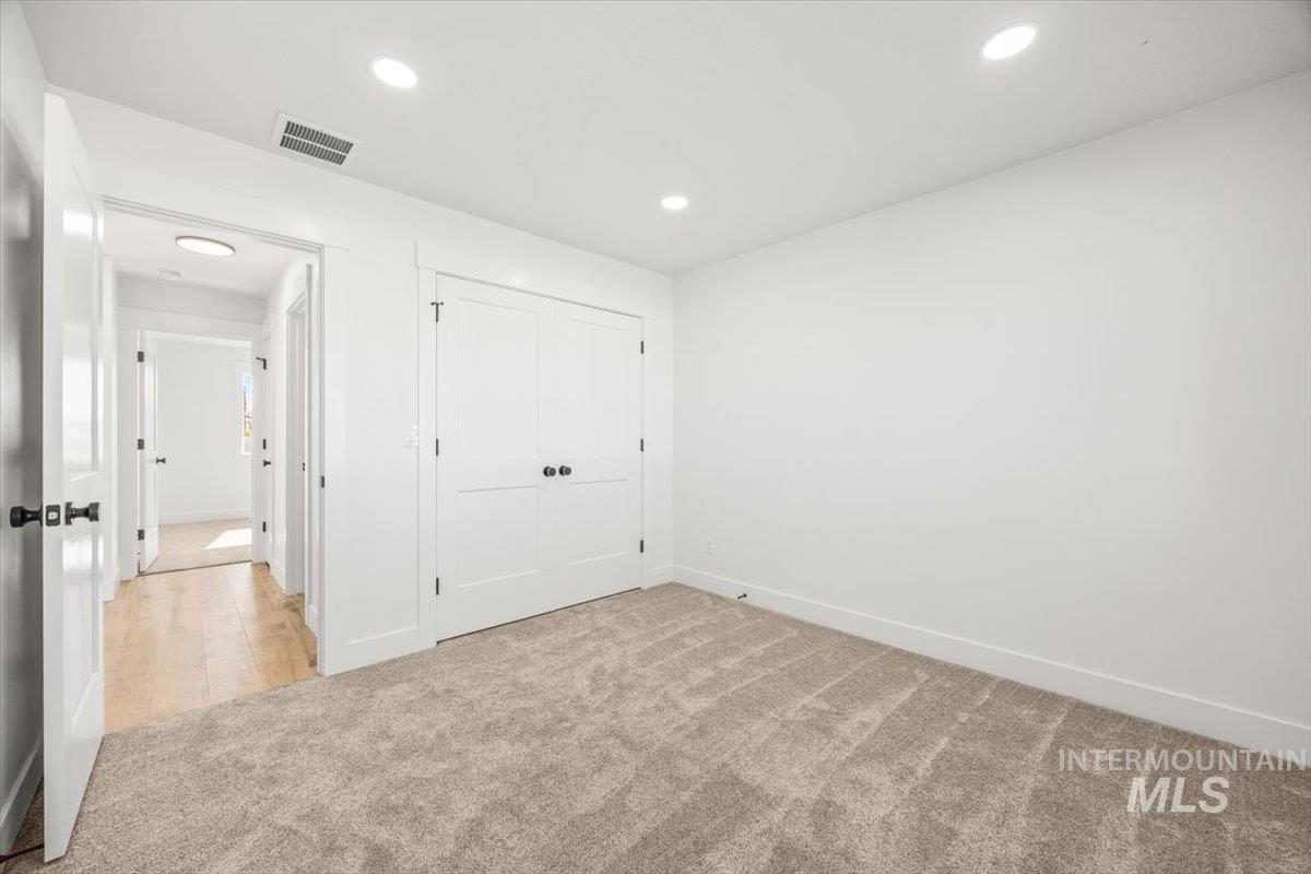 Unfurnished bedroom featuring light carpet, a closet, and recessed lighting