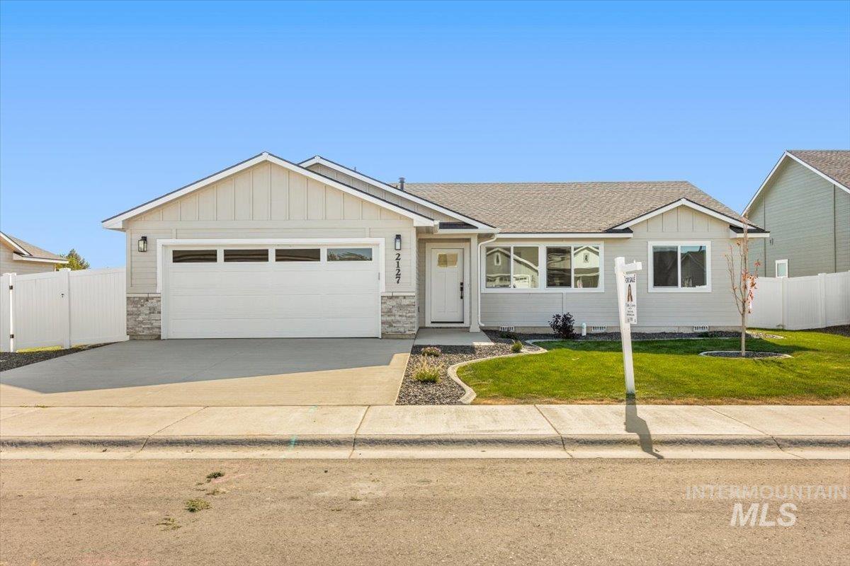 View of front of house with board and batten siding, stone siding, concrete driveway, and a garage