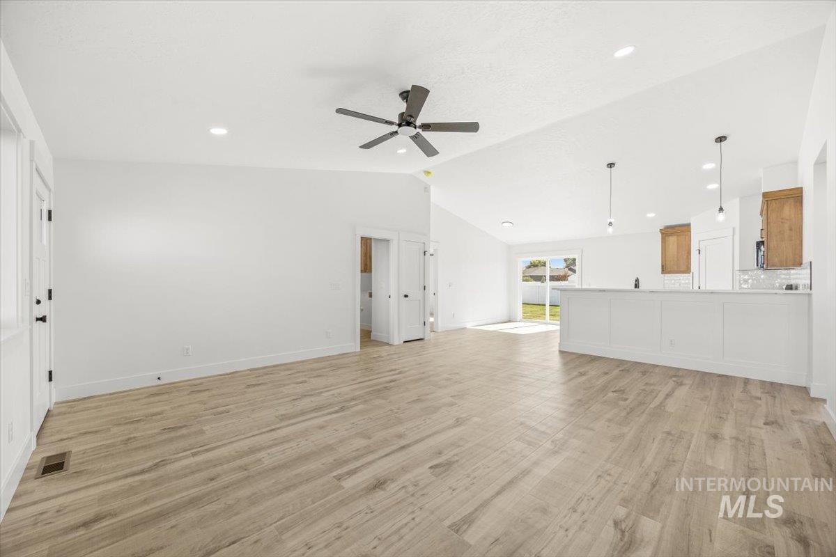 Unfurnished living room featuring light wood-style flooring, vaulted ceiling, a ceiling fan, and recessed lighting