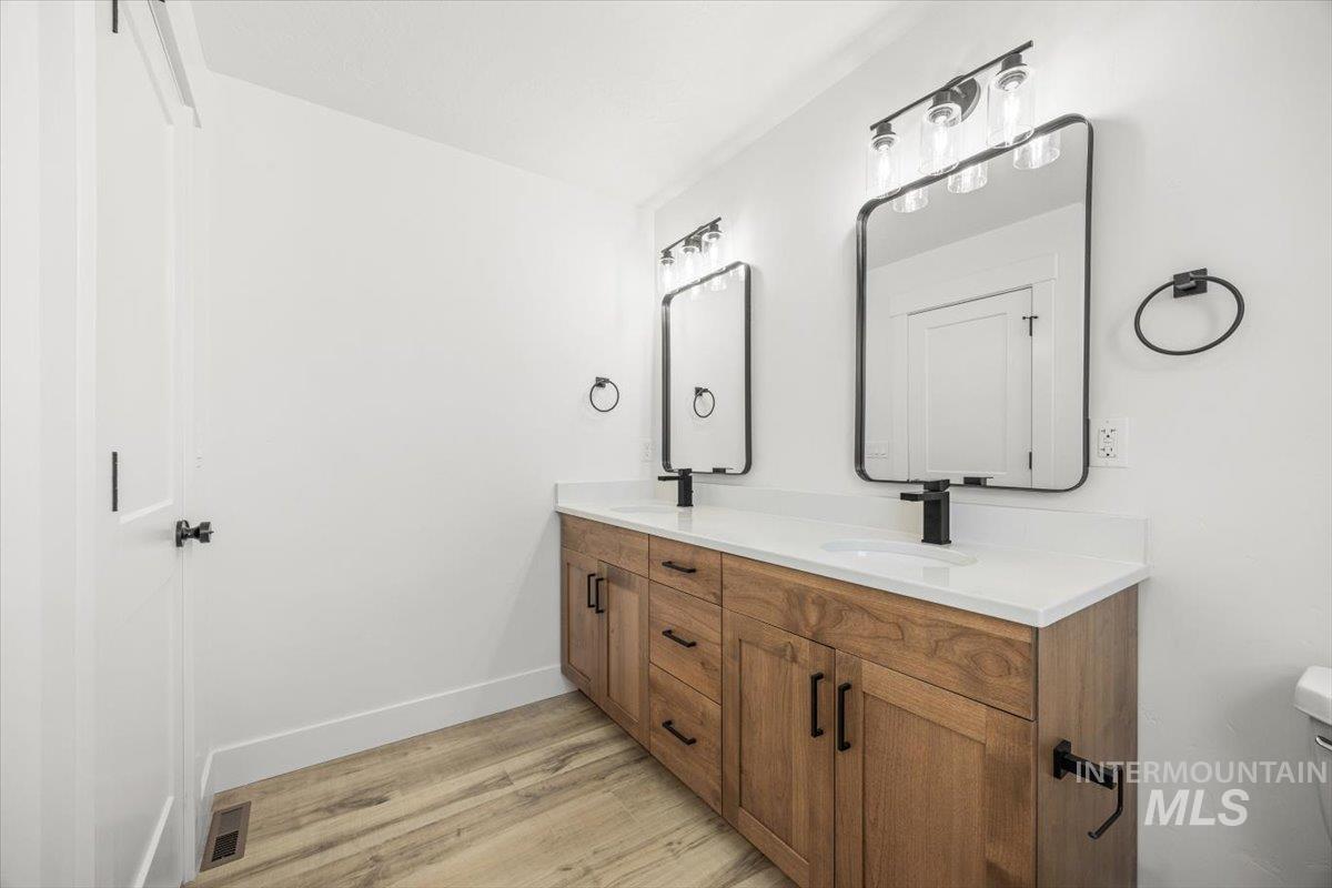 Bathroom featuring double vanity and light wood-type flooring