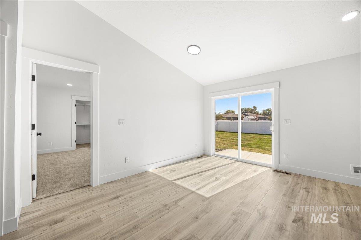 Spare room with lofted ceiling, light wood-style floors, and recessed lighting