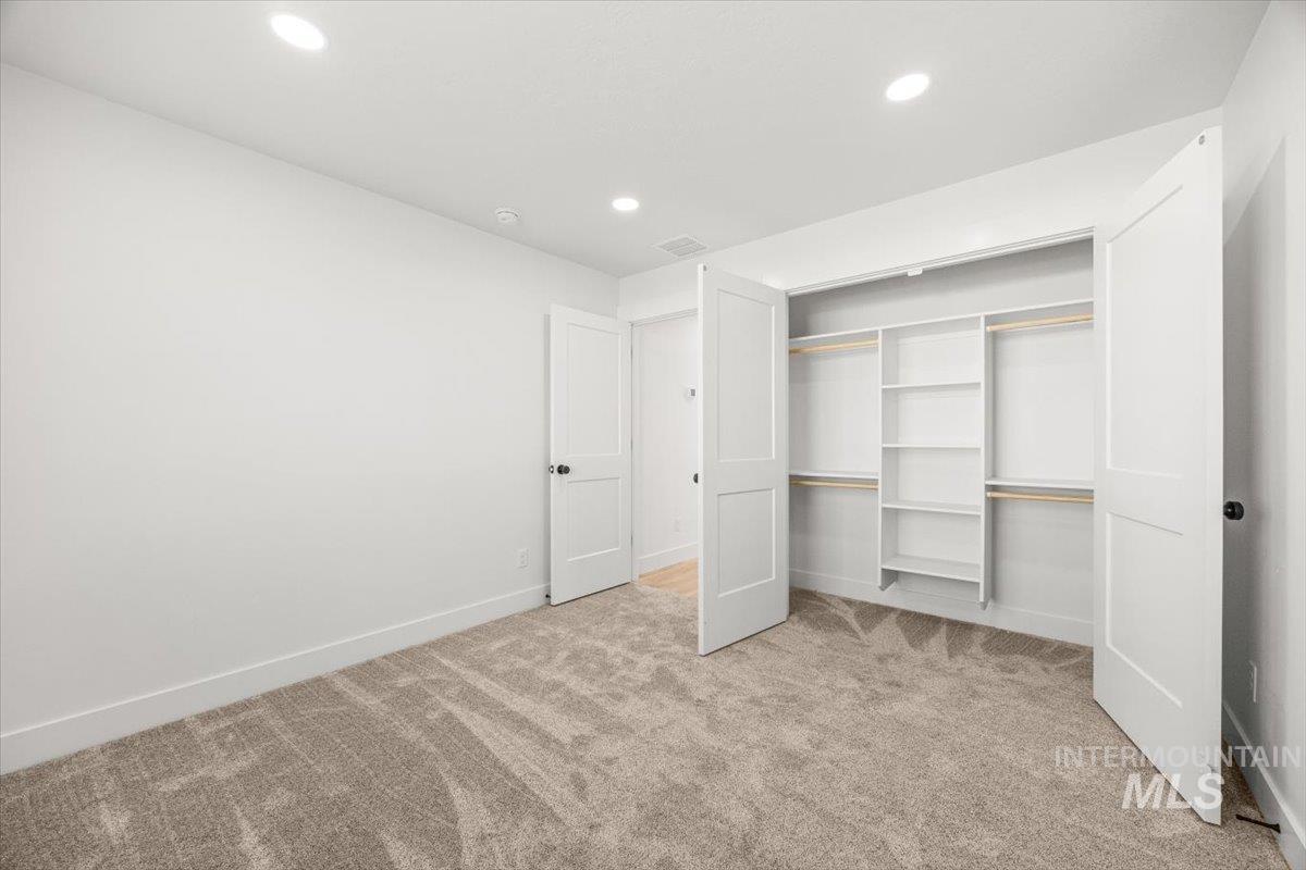 Unfurnished bedroom featuring light carpet, recessed lighting, and a closet