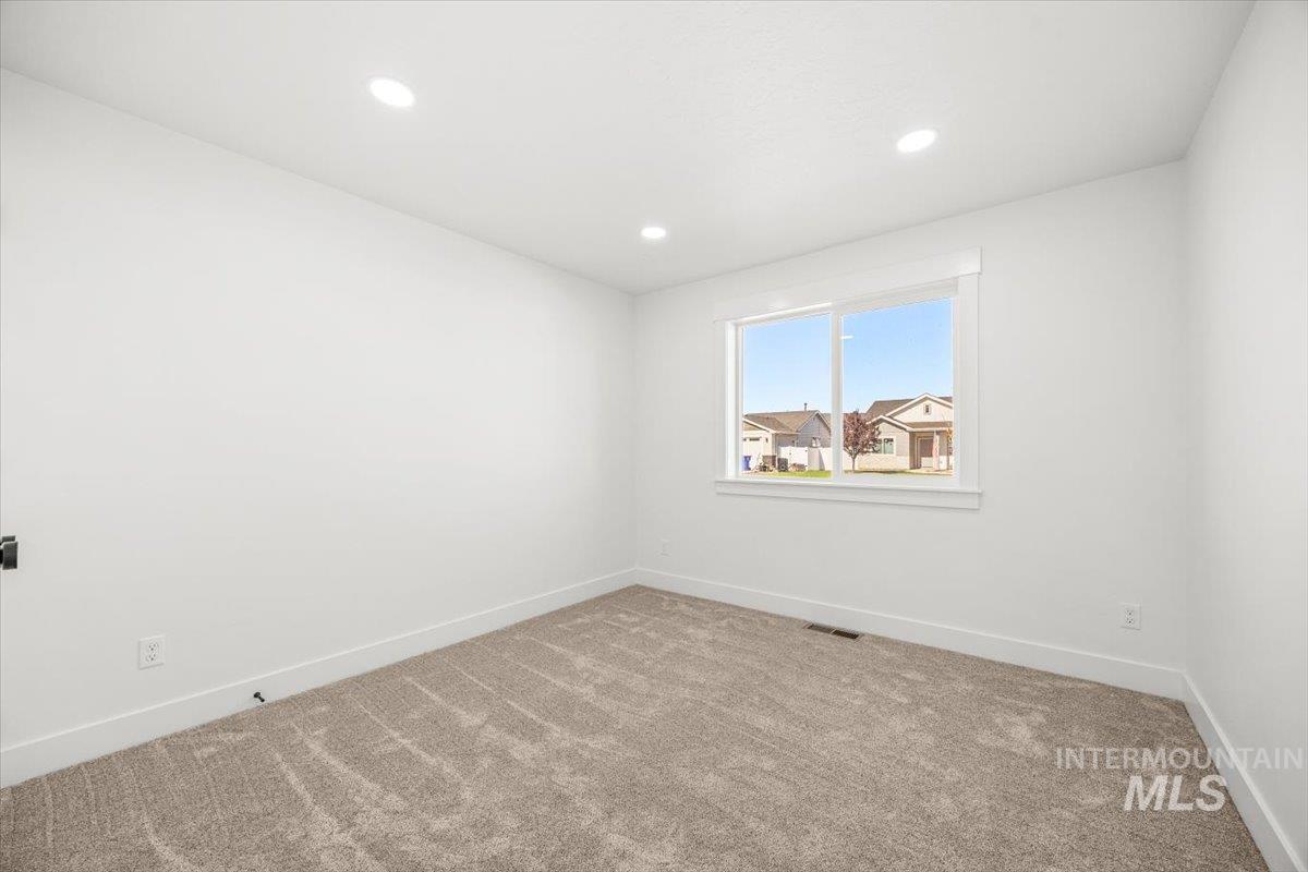 Empty room with light colored carpet and recessed lighting