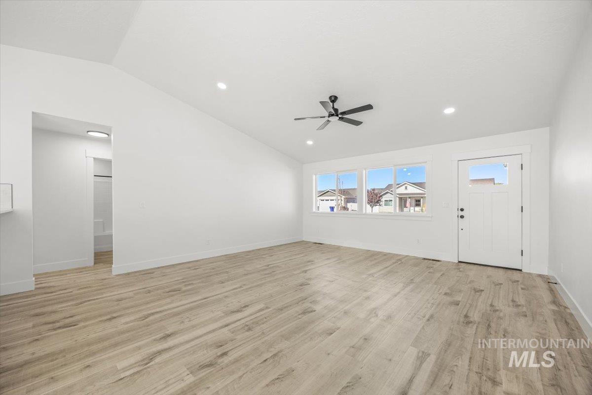 Unfurnished living room featuring vaulted ceiling, light wood-style flooring, recessed lighting, and a ceiling fan