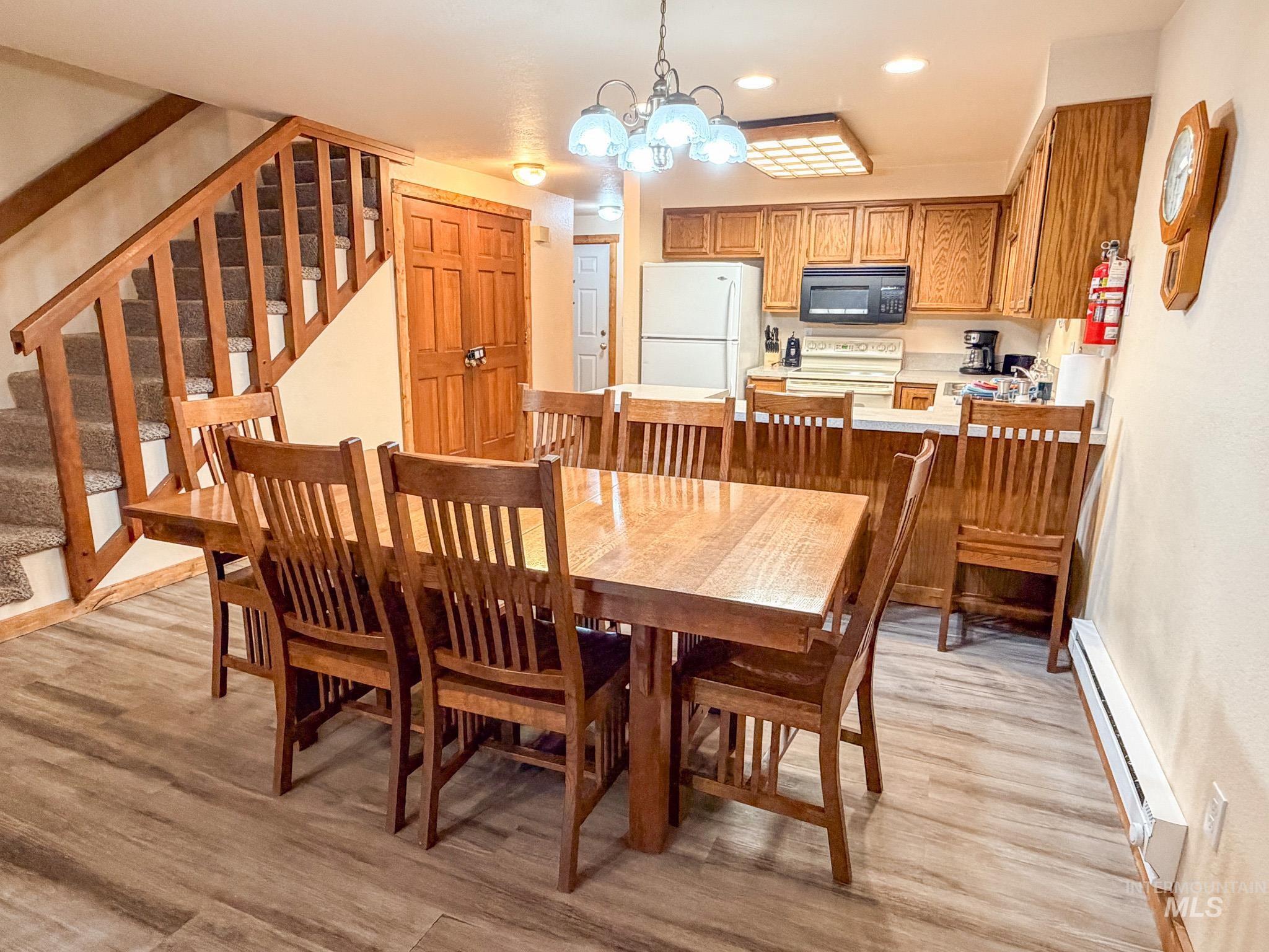 Dining space featuring a chandelier, stairs, recessed lighting, a baseboard heating unit, and light wood-style floors